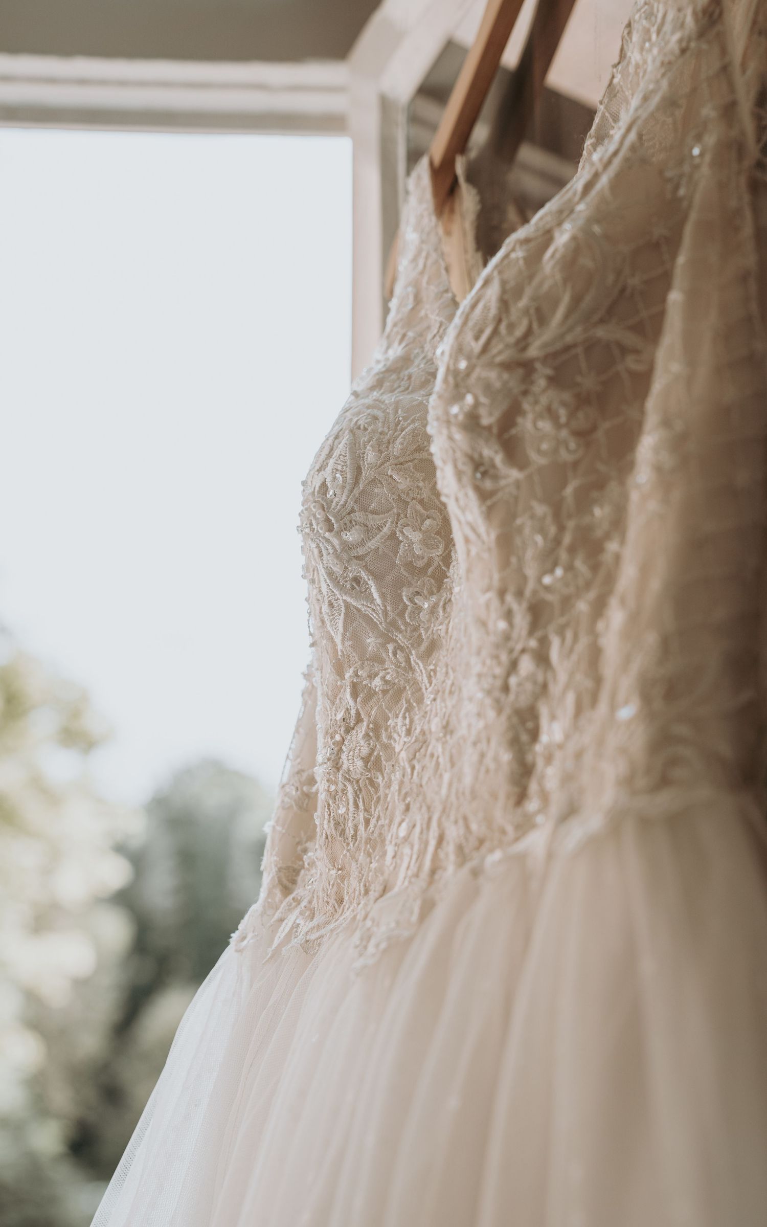 Close-up van delicaat kanten patroon op lijfje van witte trouwjurk – bruidsfotografie, bridal details, trouwdag, Nederland
