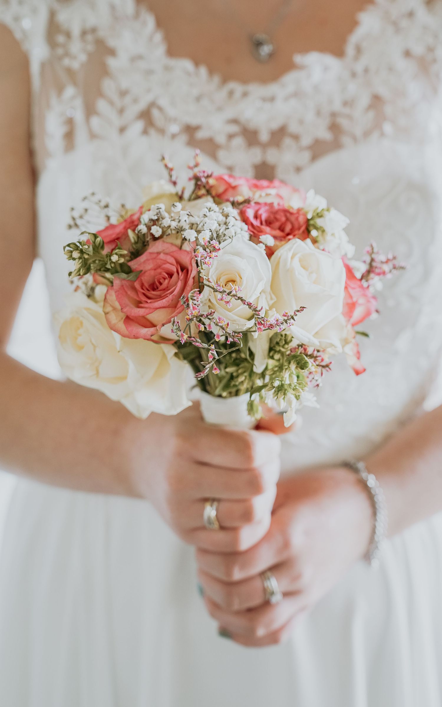 Bruidsboeket met roze en witte rozen tegen een kanten trouwjurk – bruidsfotografie, bridal details, trouwdag, Nederland
