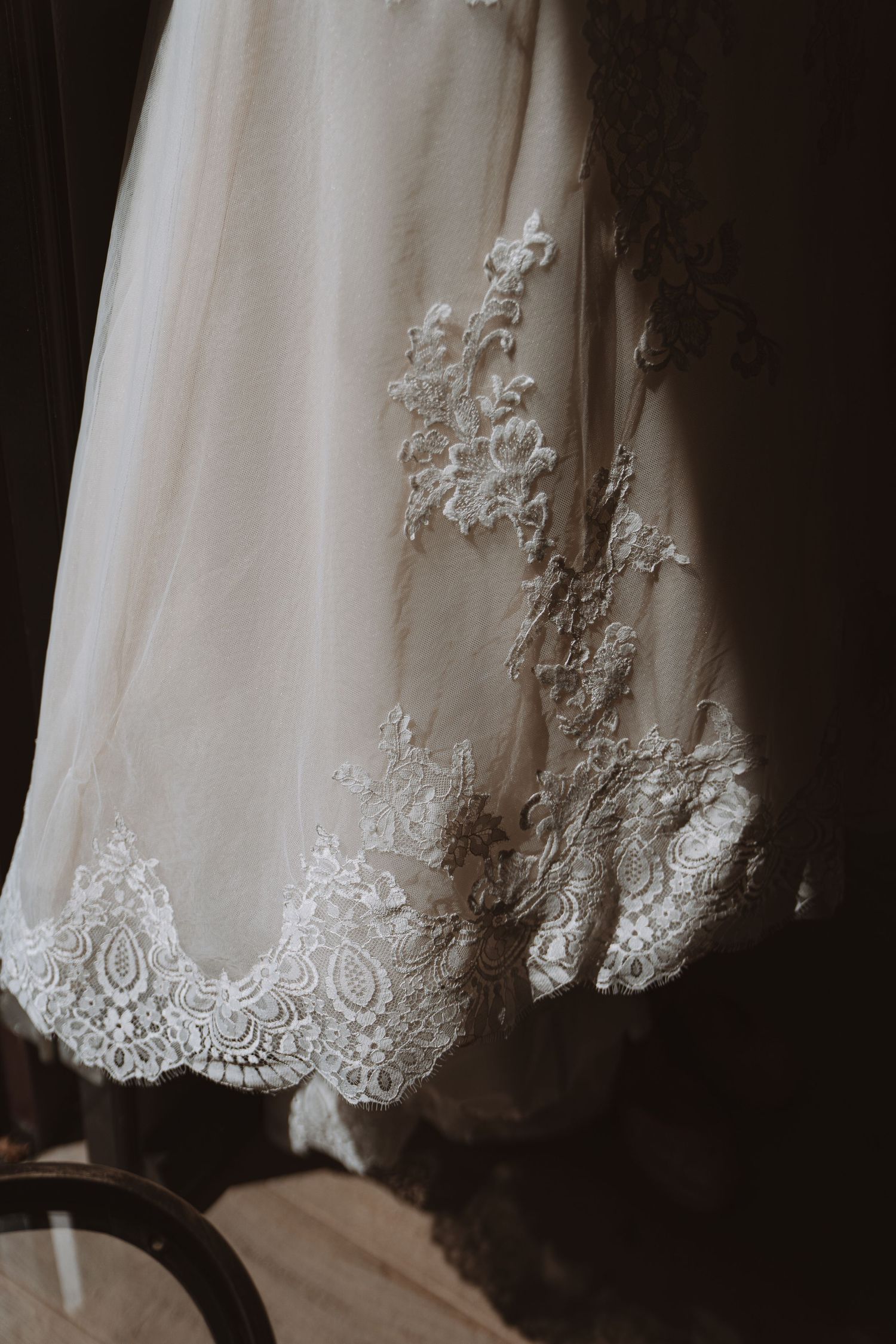 Gedetailleerde kanten zoom van een witte trouwjurk vastgelegd in dramatisch licht – bruidsfotografie, bridal details, trouwdag, Nederland
