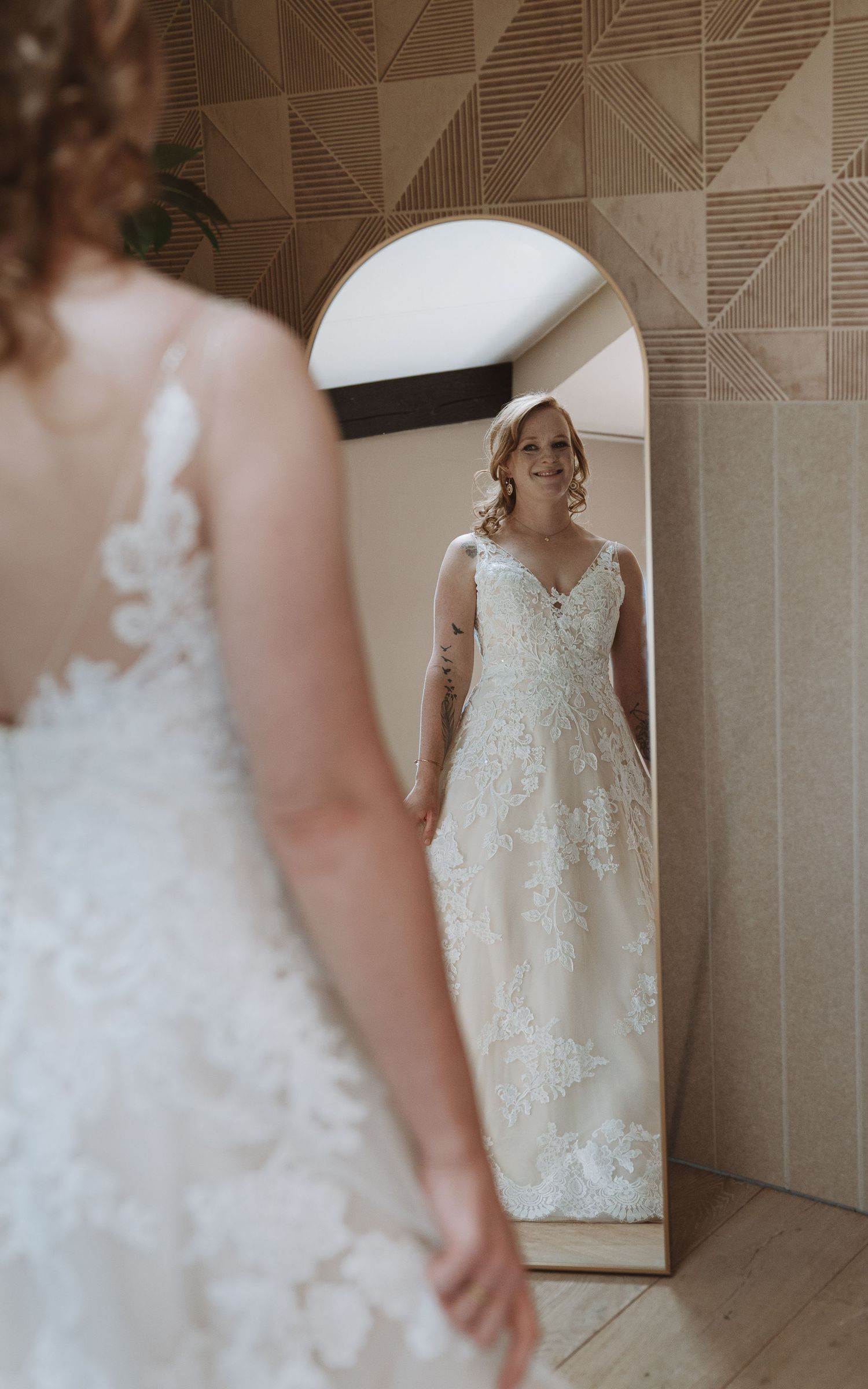 Bruid bewondert elegante trouwjurk met kanten details in volle lengte spiegel – bruidsfotografie, bridal details, trouwdag, Nederland