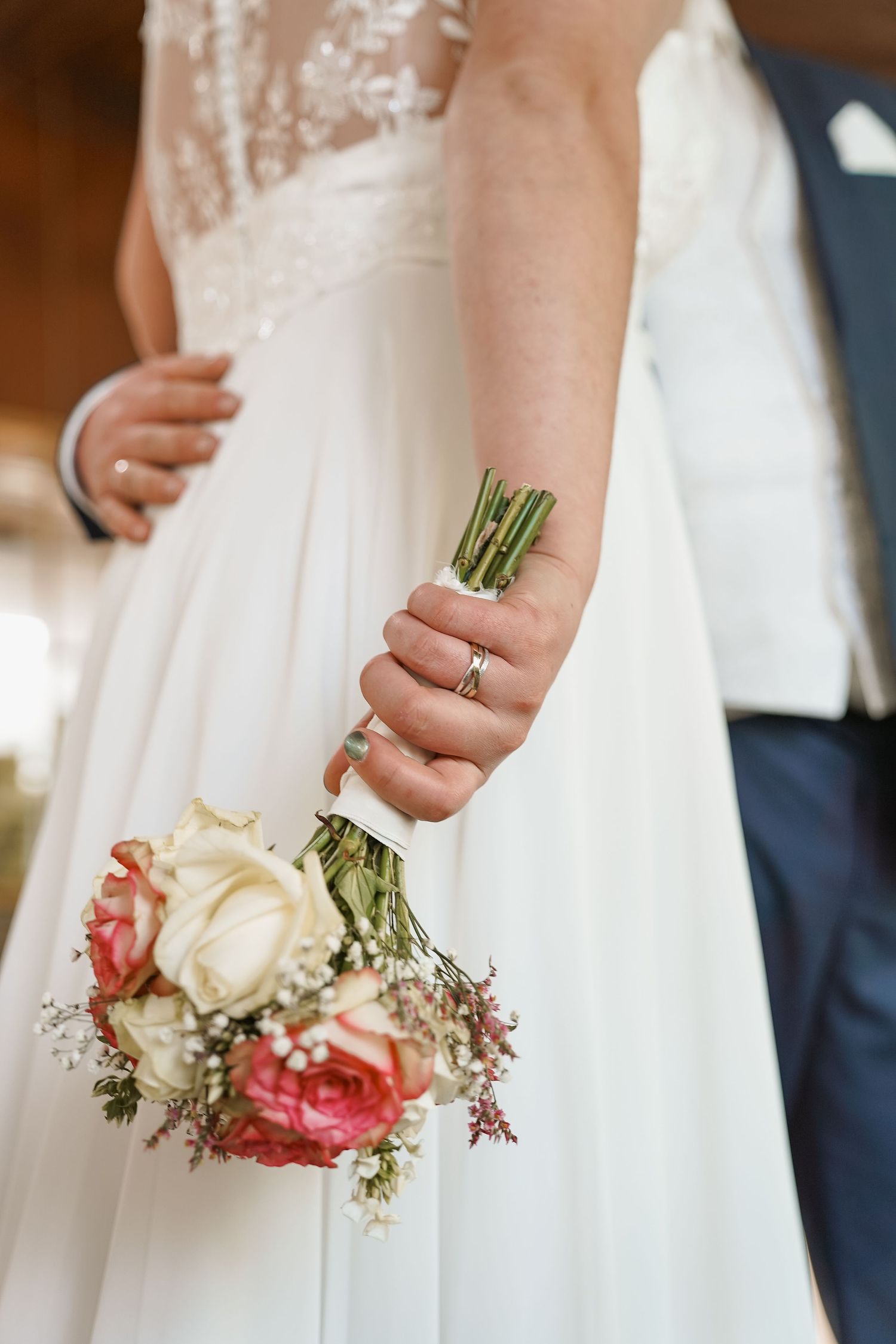 Delicaat roze-wit bruidsboeket met rozen tegen een vloeiende witte trouwjurk – bruidsfotografie, bridal shoot, bridal details, trouwdag