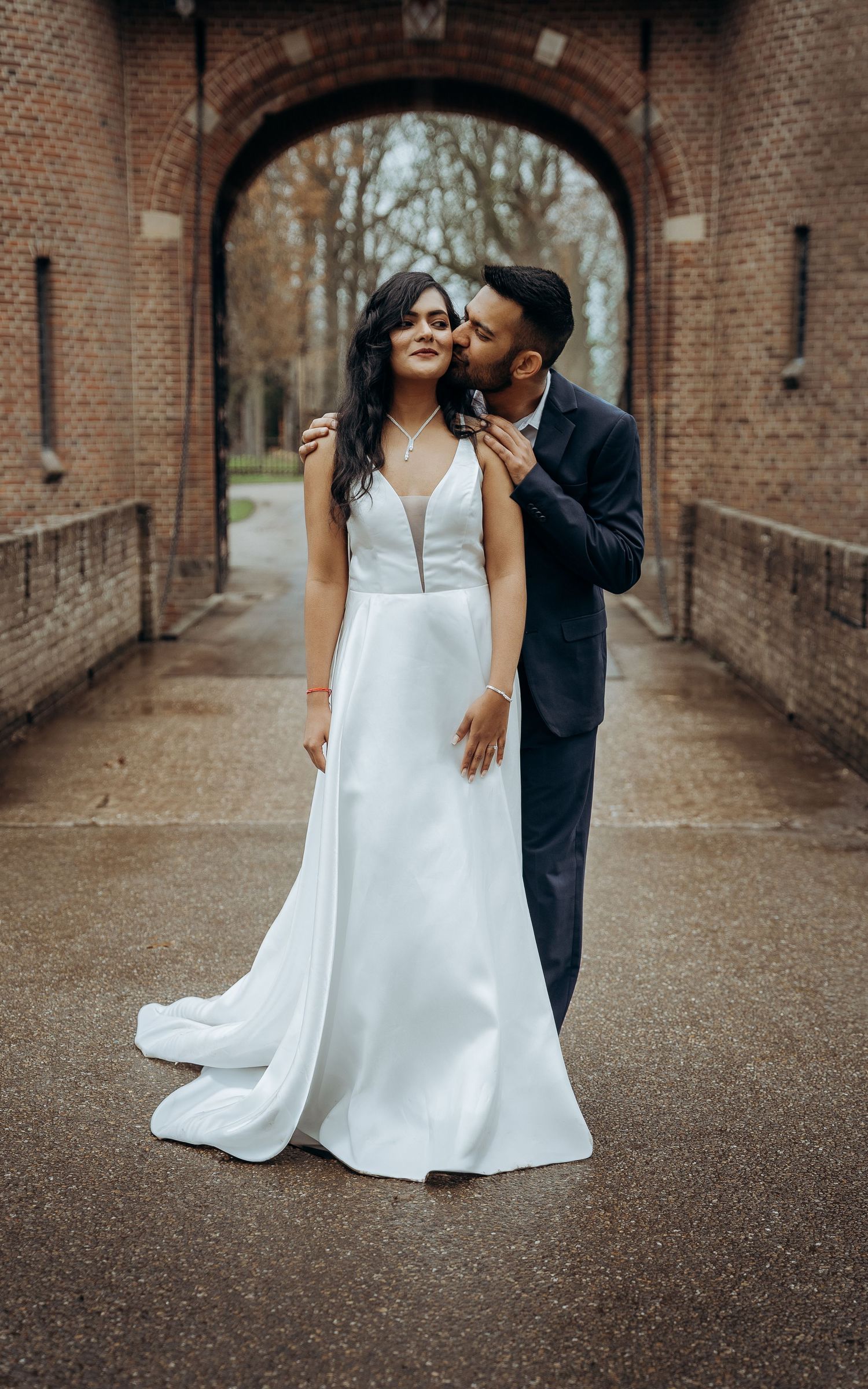 Romantisch koppel poseert in bakstenen boog bij Kasteel de Haar – bruidsfotografie, trouwdag, romantisch, Nederland