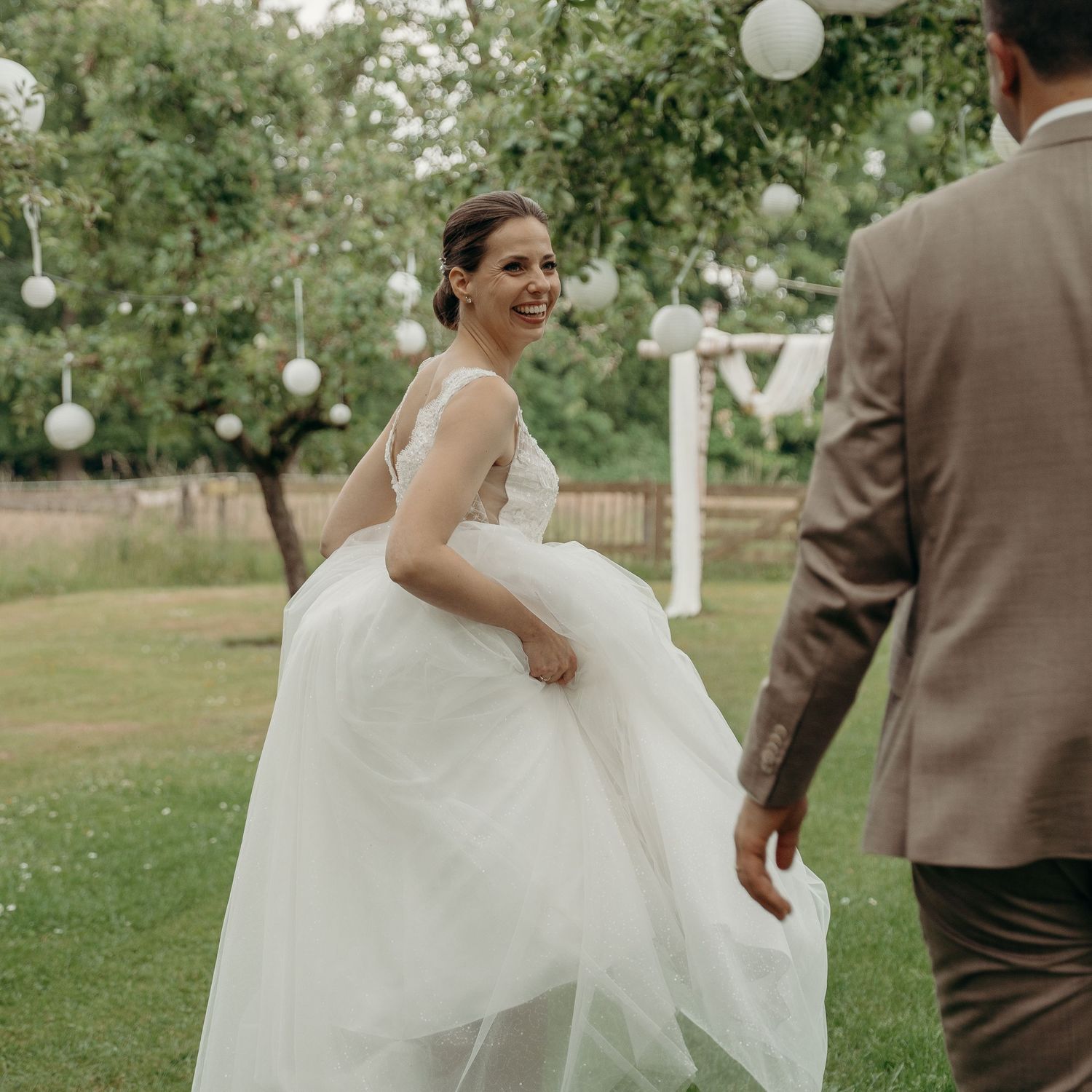 Bruidspaar geniet van speelse momenten in tuin met witte decoraties, Klooster Nieuwkerk Goirle – bruidsfotografie, trouwdag, Nederland