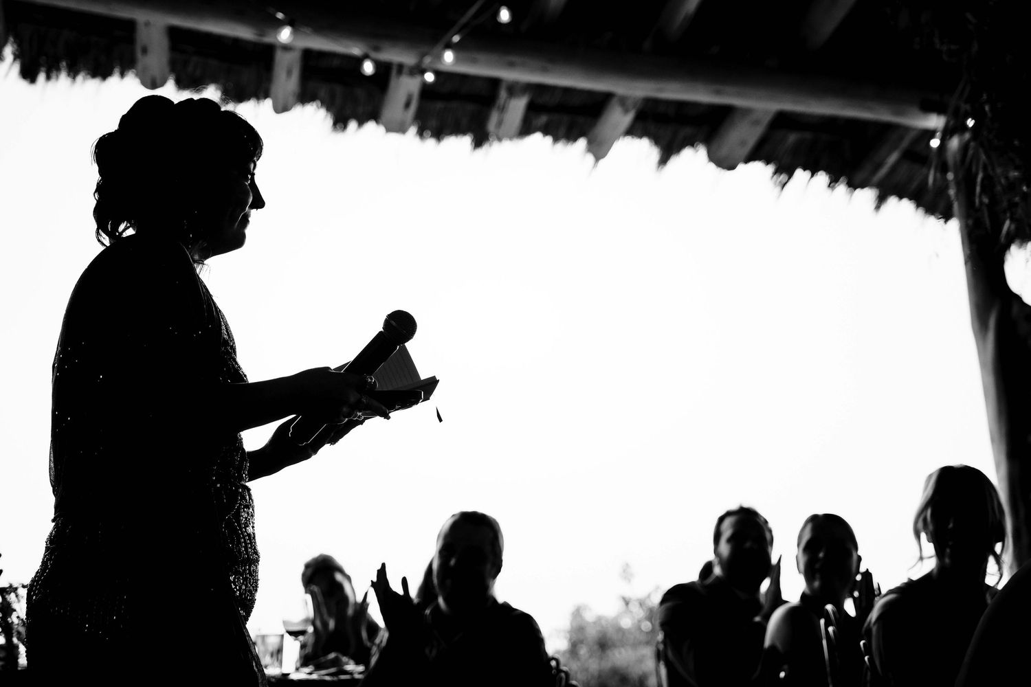 Silhouettes of concert crowd with raised hands against bright stage lights during live music performance.
