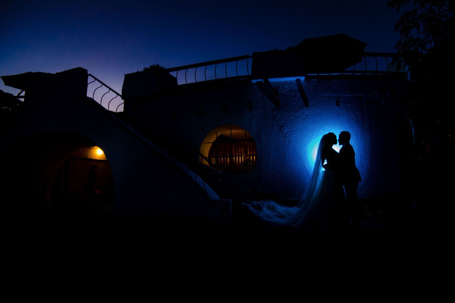 Silhouettes against a dark blue evening sky with architectural elements in the background.