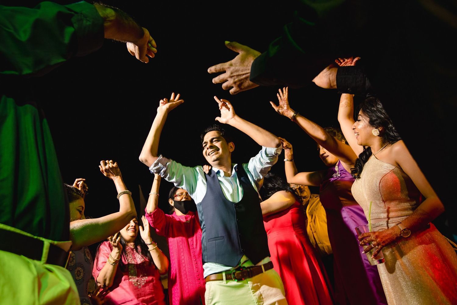 Colorful nighttime dance party with guests celebrating under dramatic lighting.