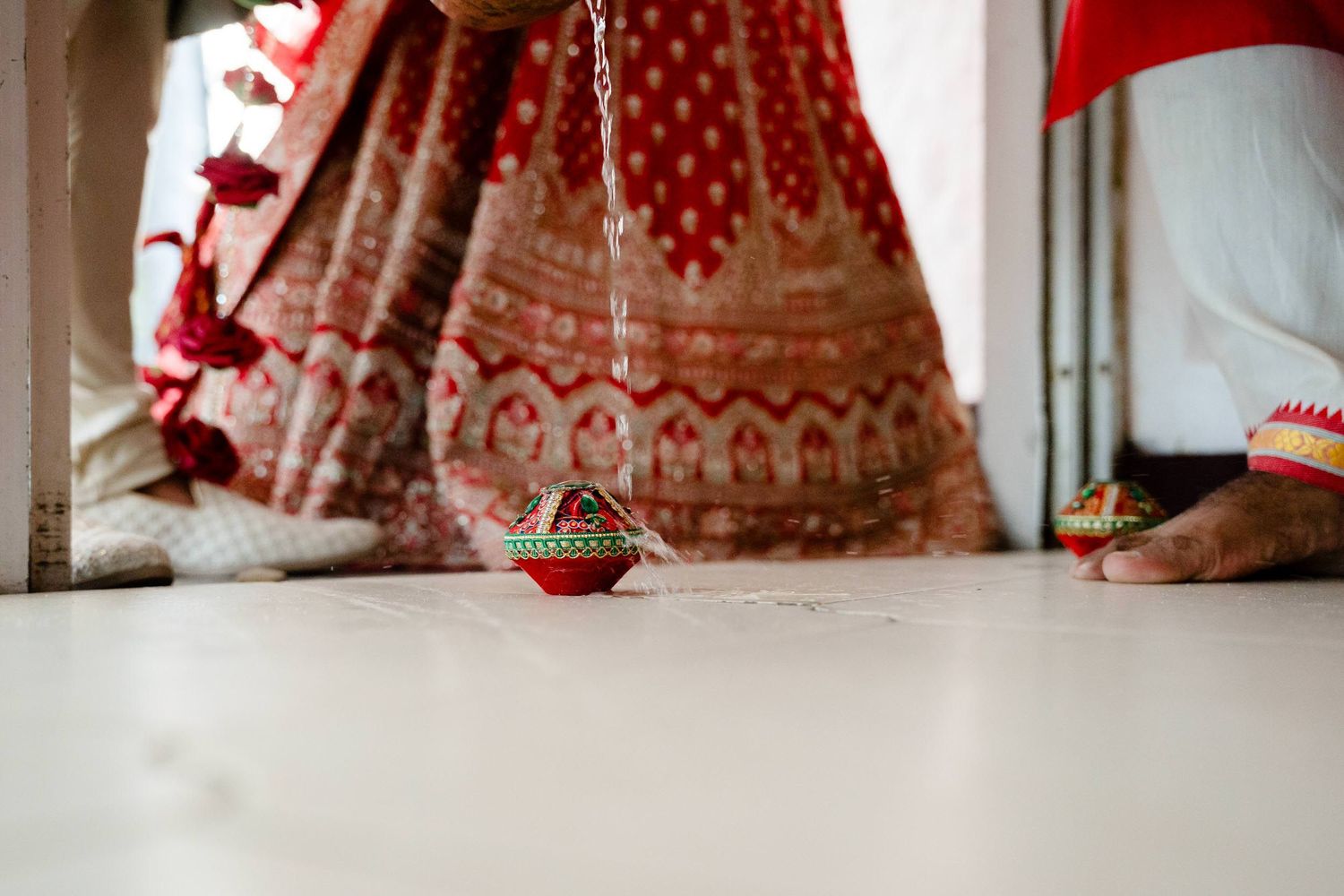 A close-up detail of a traditional red Indian bridal lehenga with intricate gold embroidery and embellishments.