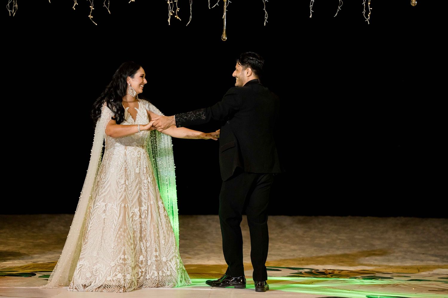 A couple shares a romantic dance moment on an illuminated dance floor during a wedding celebration.