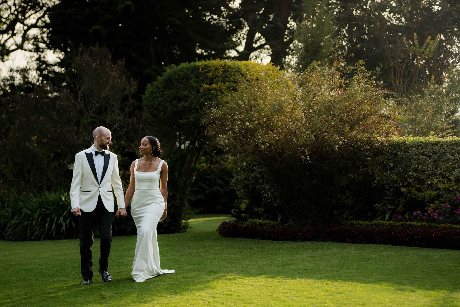A bride and groom share an intimate moment on a lush green lawn during their outdoor wedding.