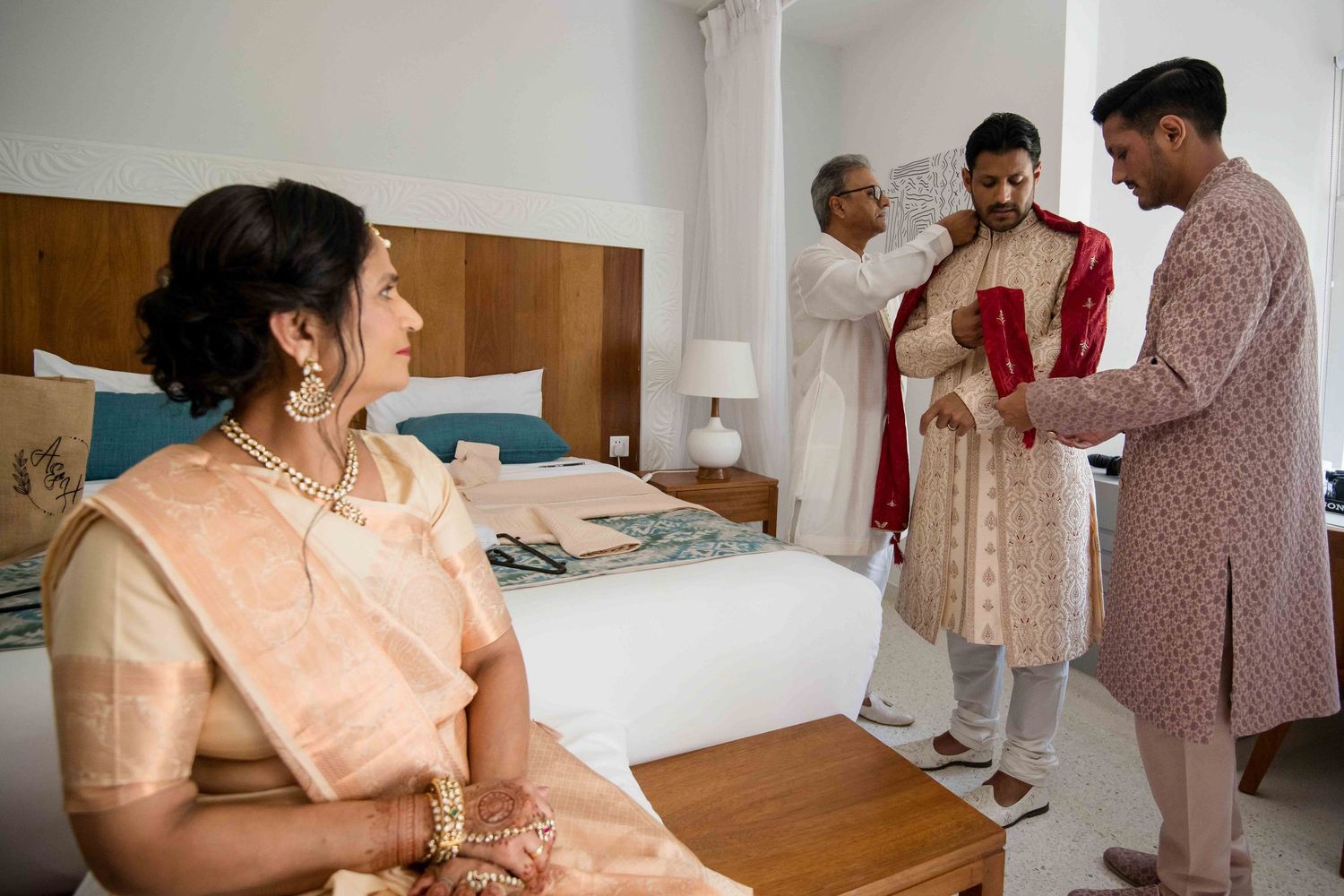 People gather in a room wearing pink and white outfits while interacting with each other during a special occasion.