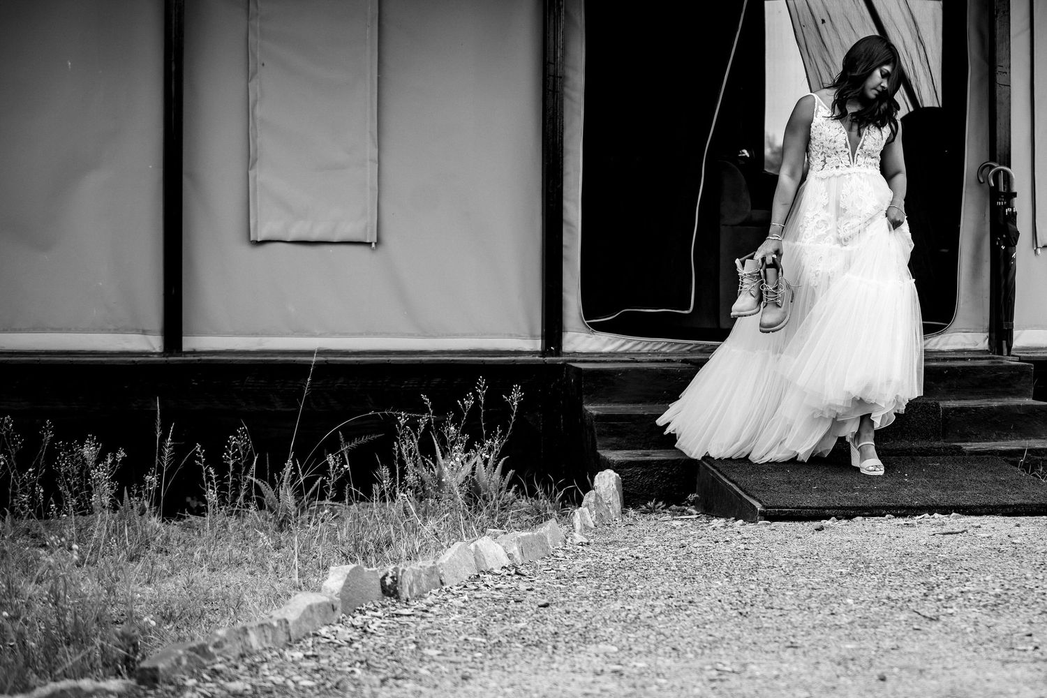 Wedding dress silhouette against white walls and stone pathway.