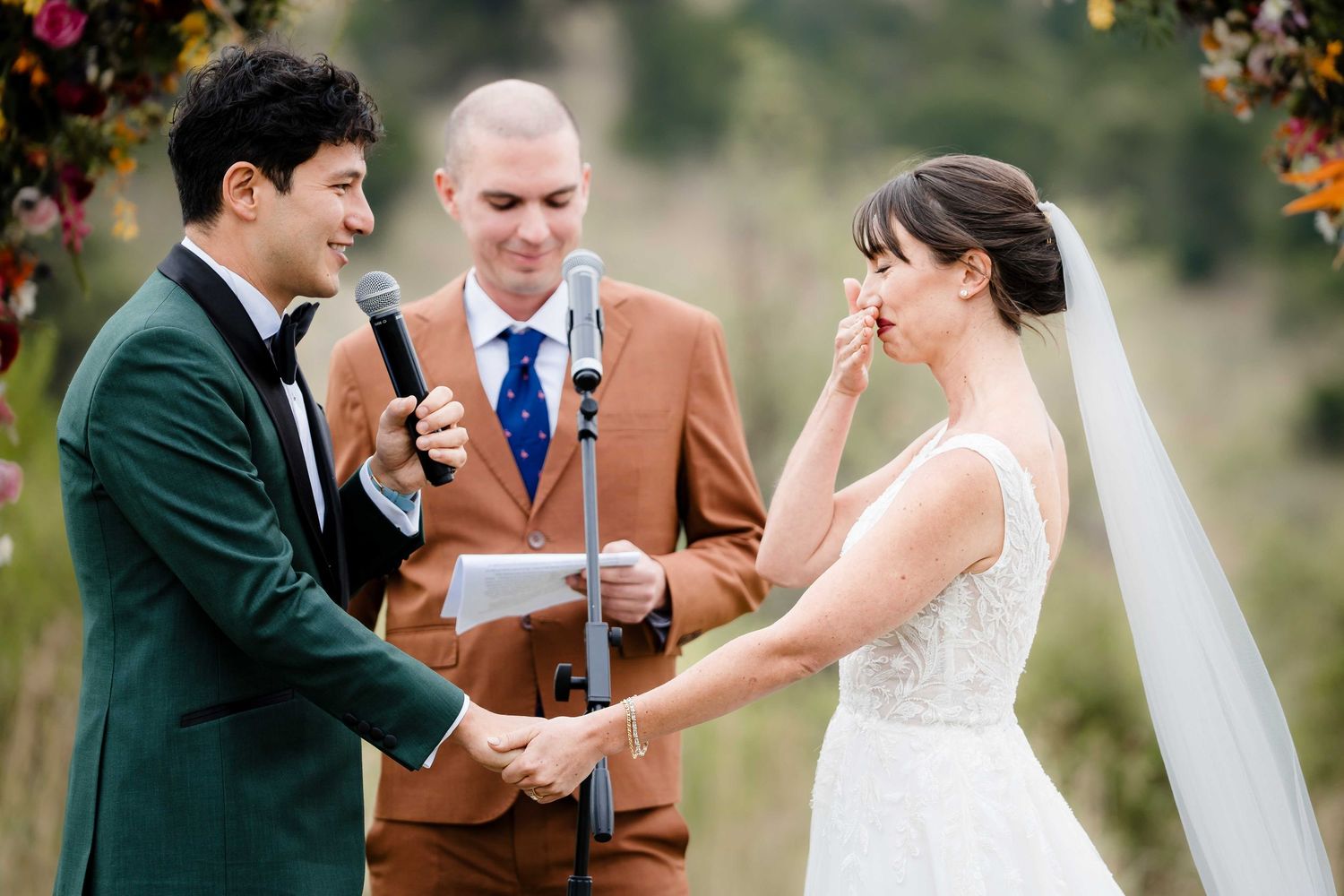 A couple shares an emotional moment during their outdoor wedding ceremony in a natural setting.