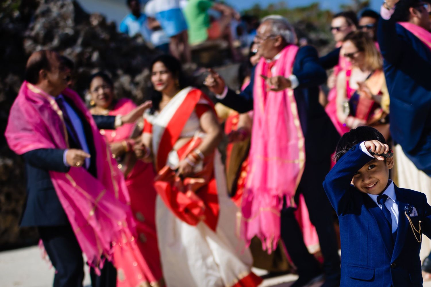 Crowd of people wearing bright pink and blue clothing at an outdoor celebration.