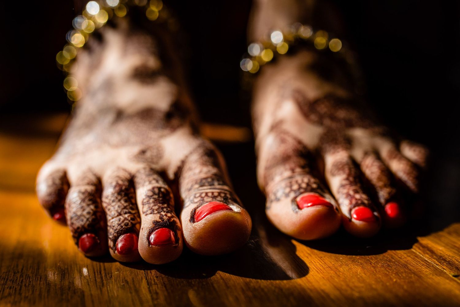 Close-up of decorated feet with henna and toe rings in traditional Indian bridal style.