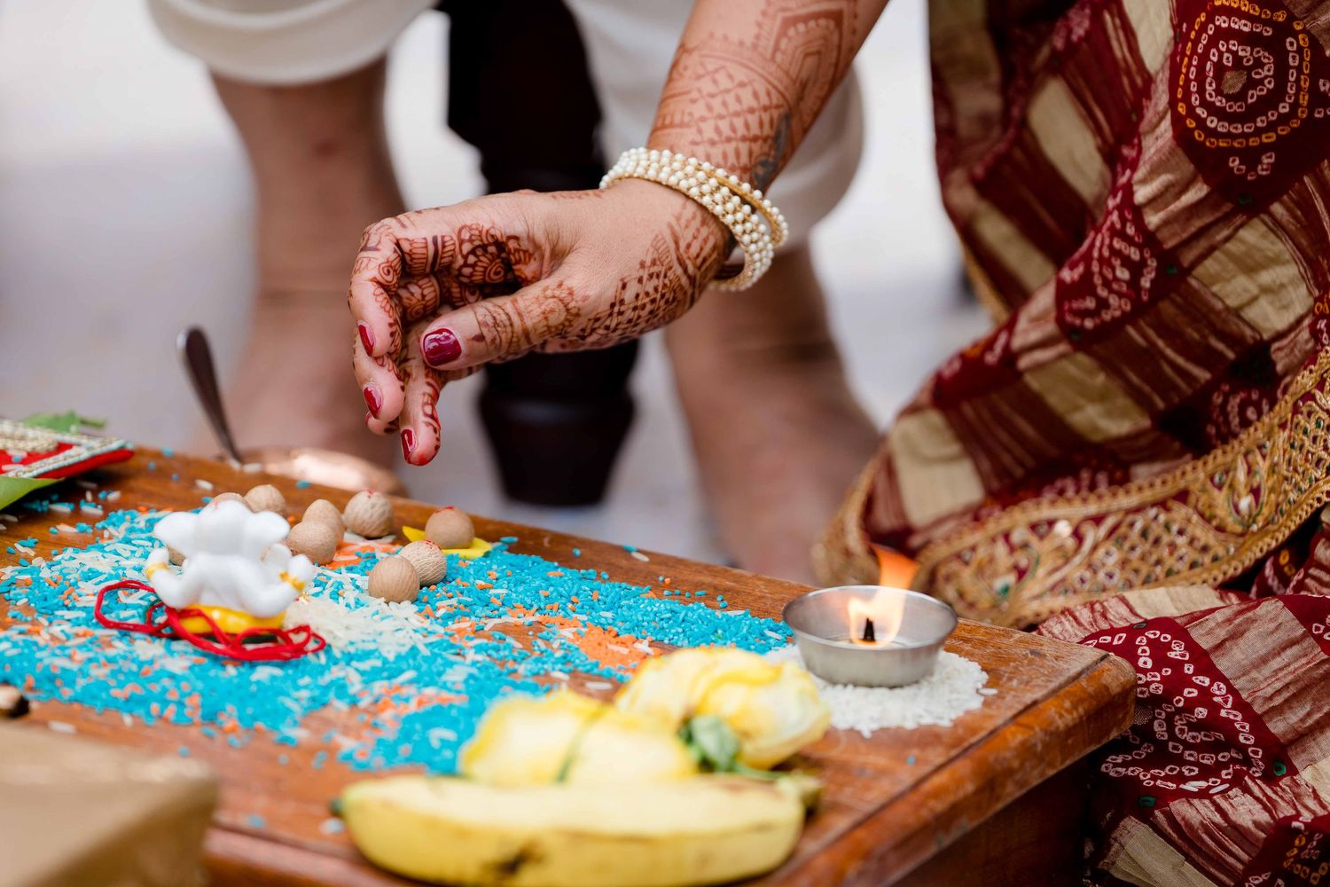 Traditional Indian henna-adorned hands prepare colorful food on a decorative turquoise plate.