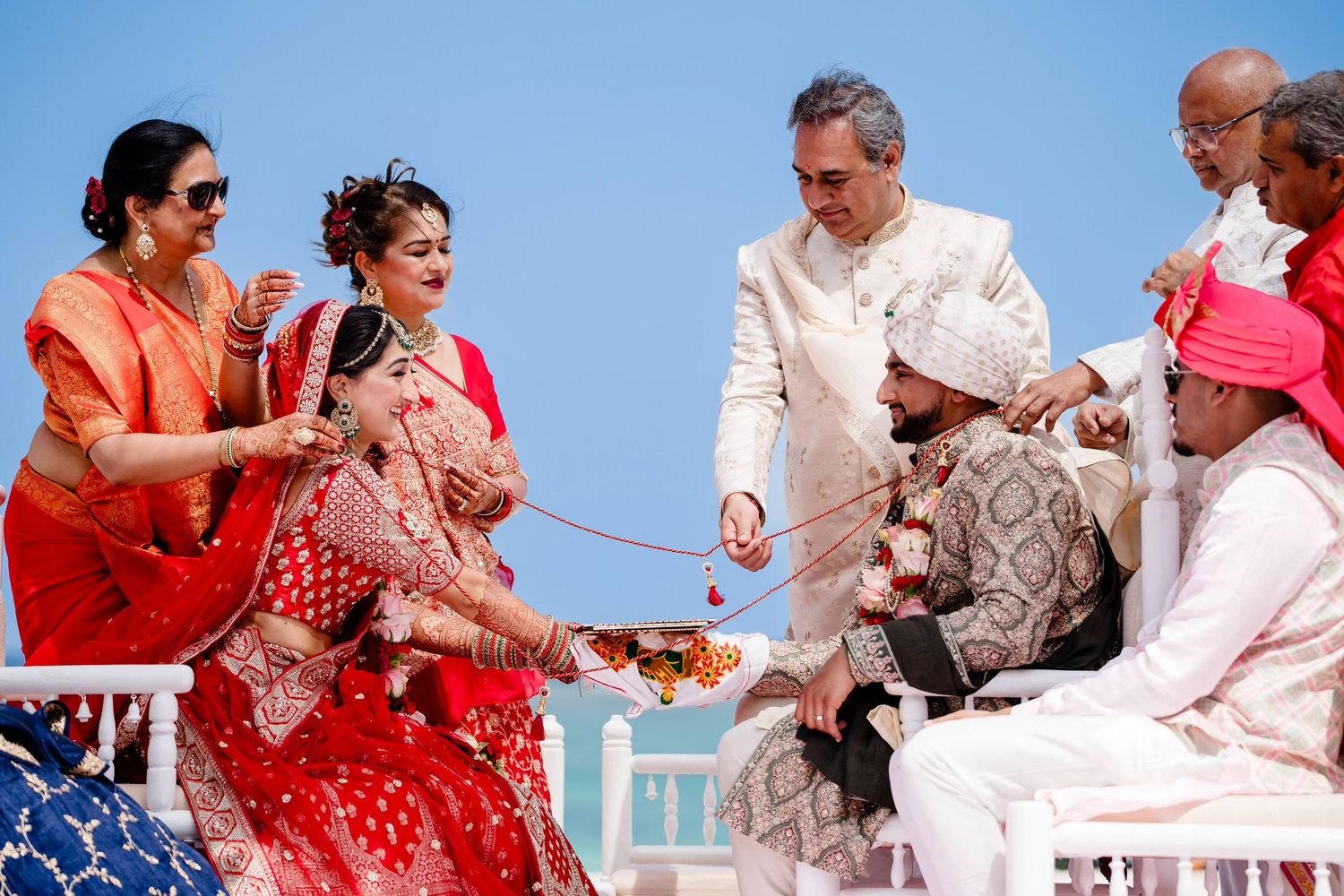 A group of people dancing and celebrating at a wedding reception with colorful dresses and joyful movements.