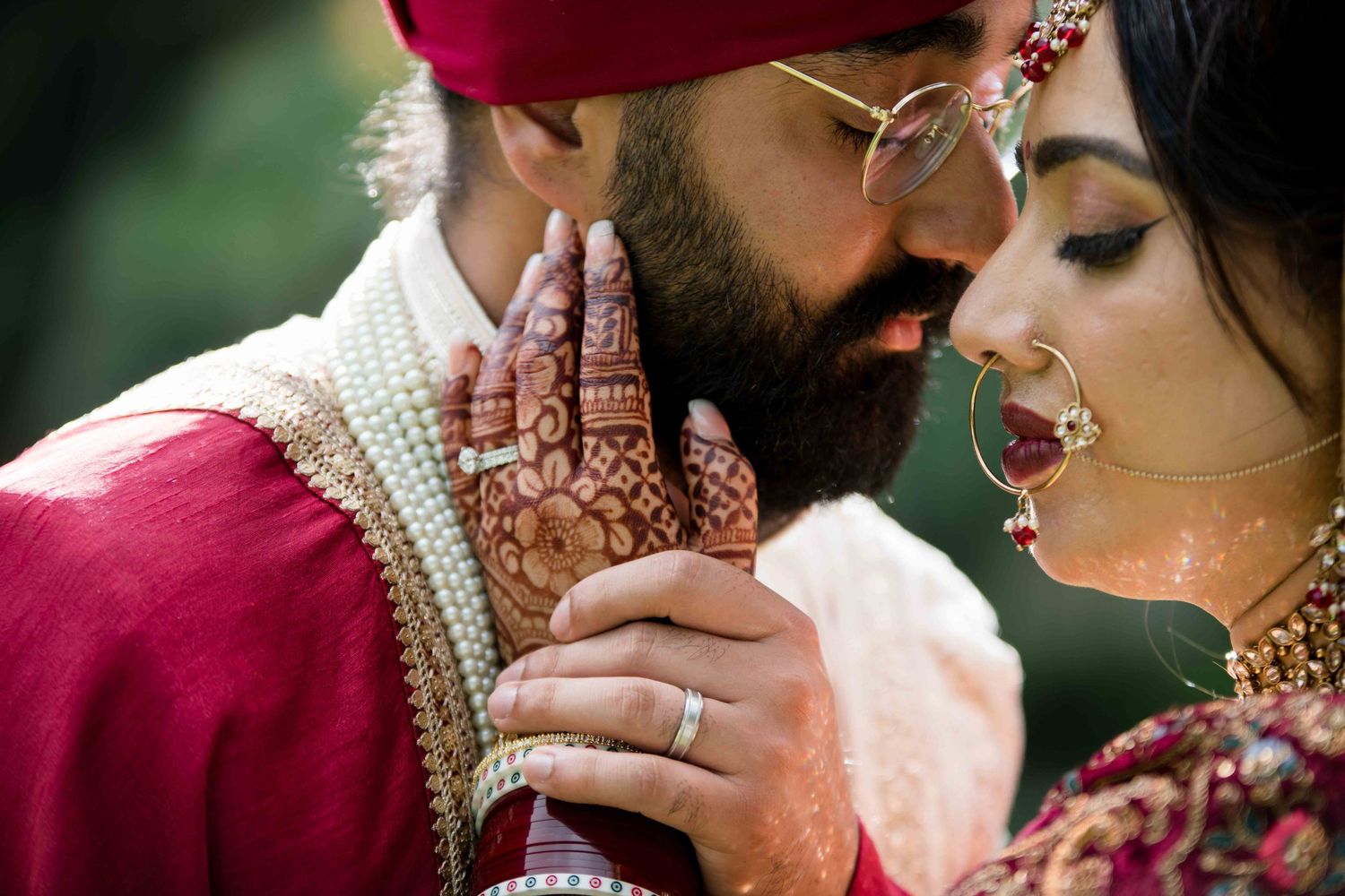 Close-up detail of traditional Indian wedding jewelry and attire in rich red tones.