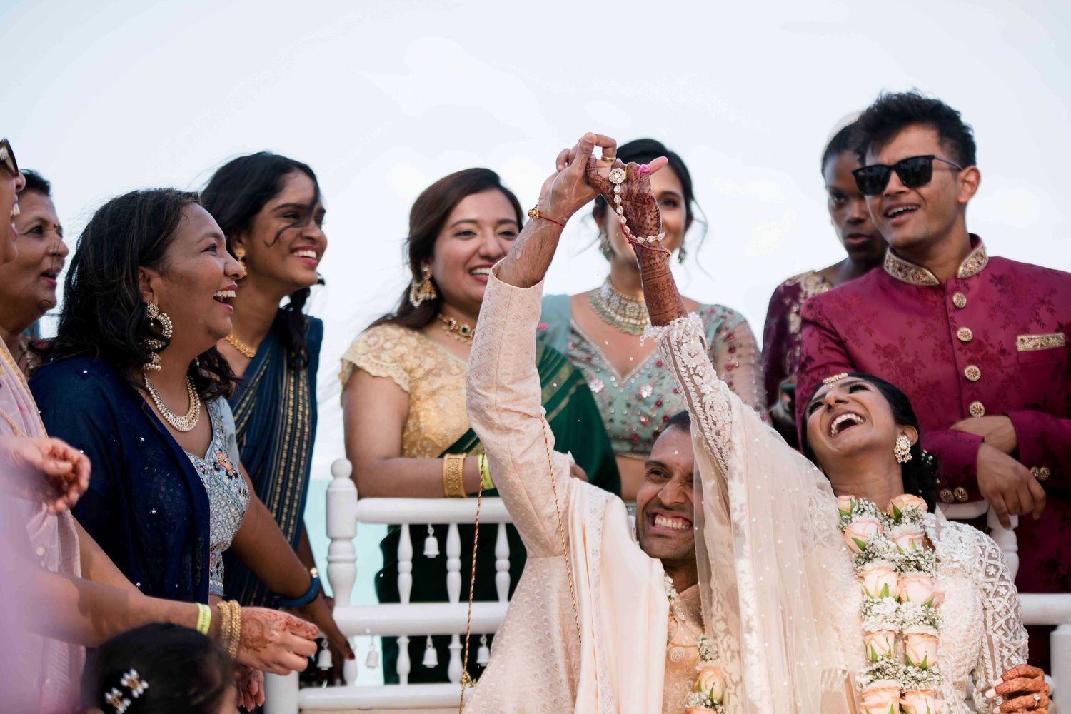 A joyful candid moment of wedding guests laughing together at an outdoor celebration.