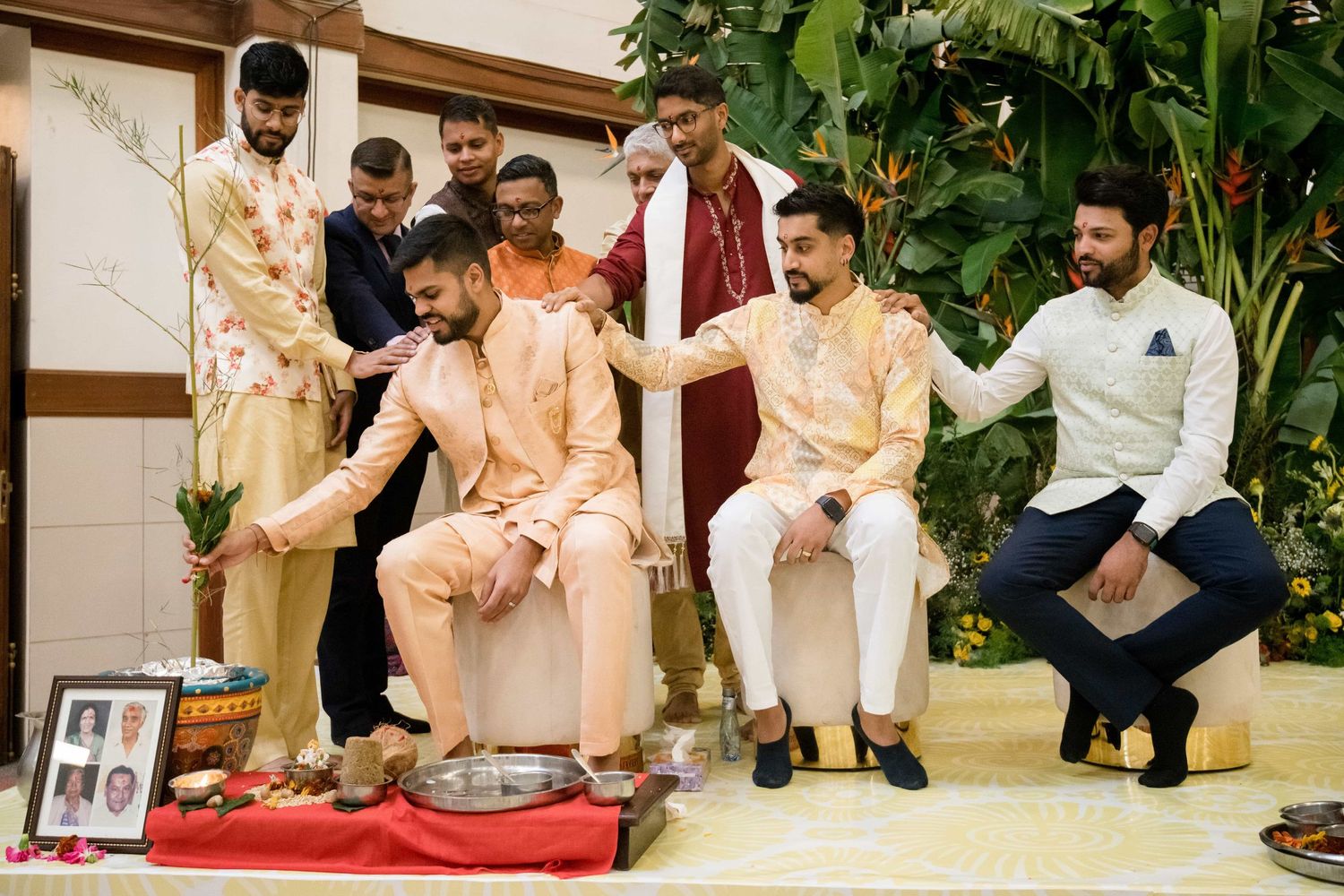 Group seated for traditional Indian ceremony wearing cream and peach colored formal attire.