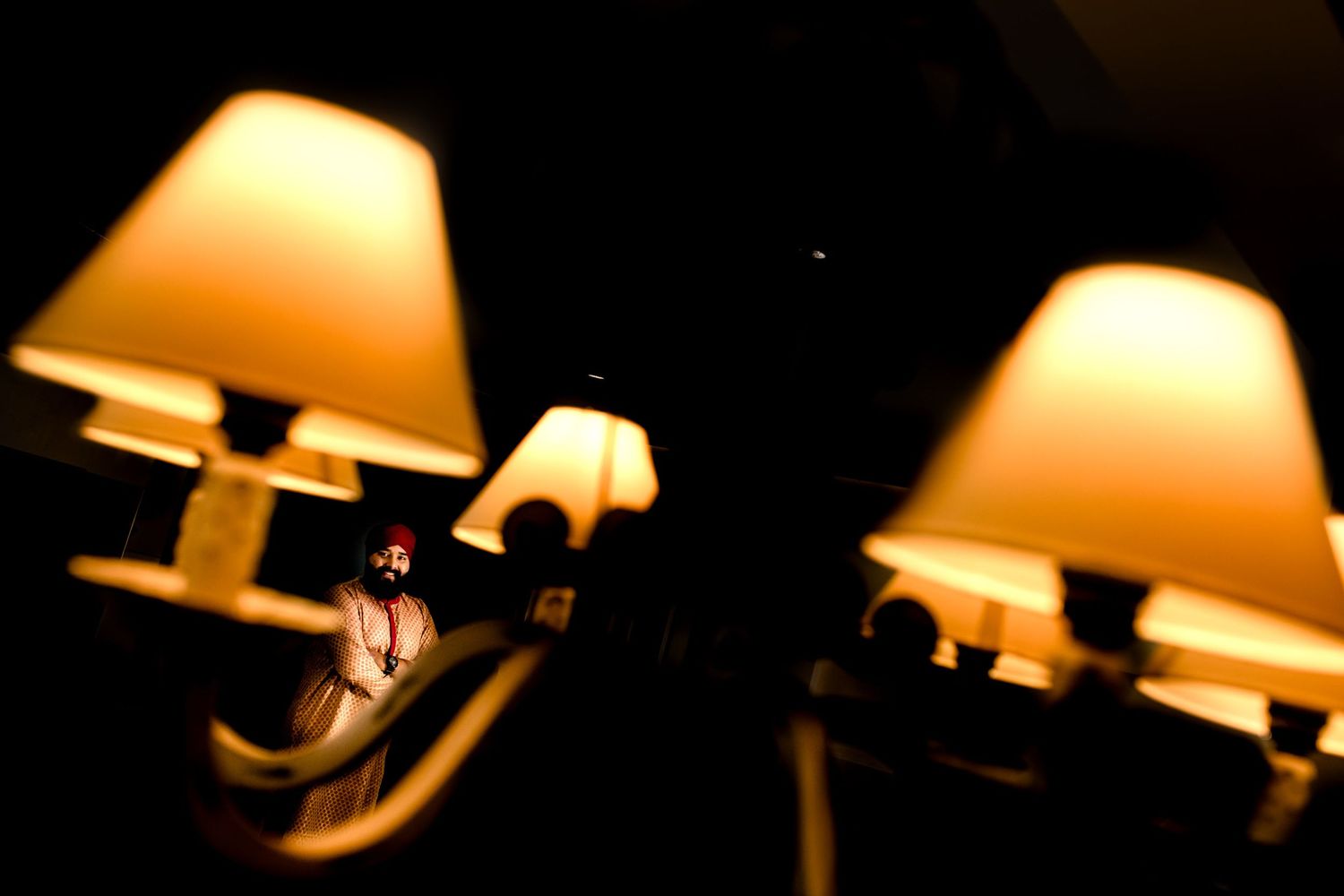 Warm glowing wall sconces with lampshades cast a cozy amber light against a dark background.