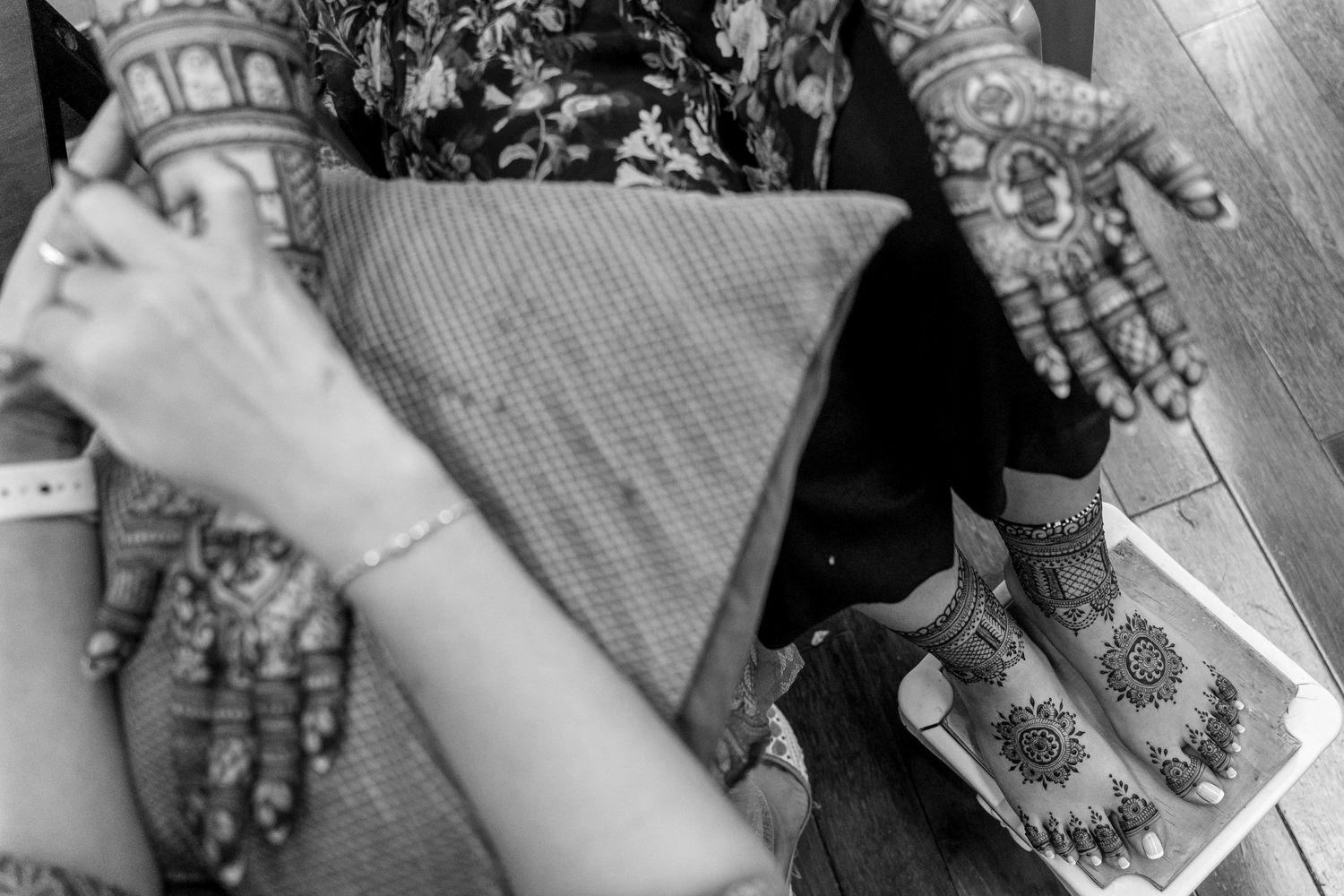 Black and white image of decorated hands holding wedding documents during ceremony.