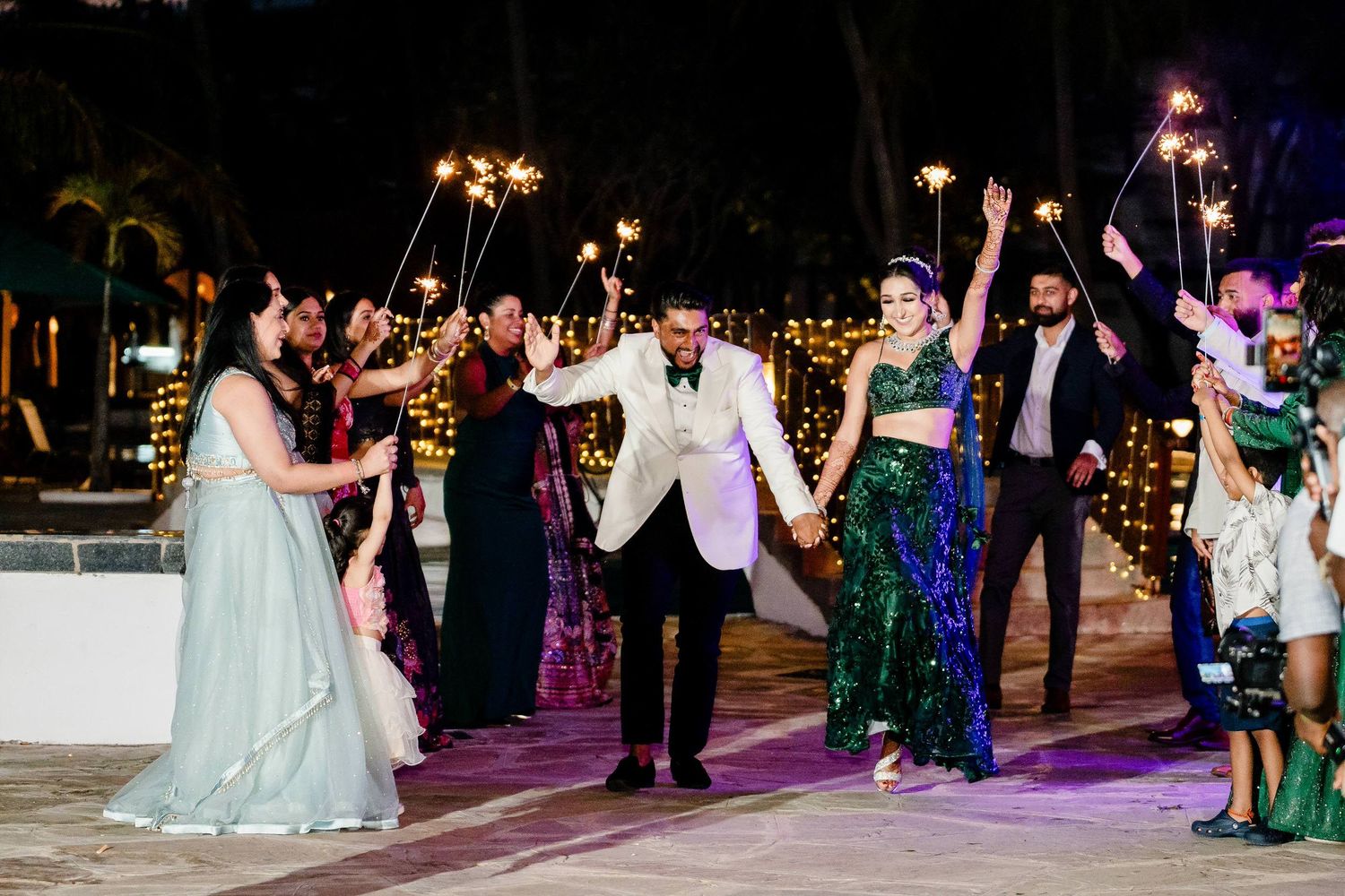 Wedding guests dance together on a colorful illuminated dance floor during an evening reception celebration.