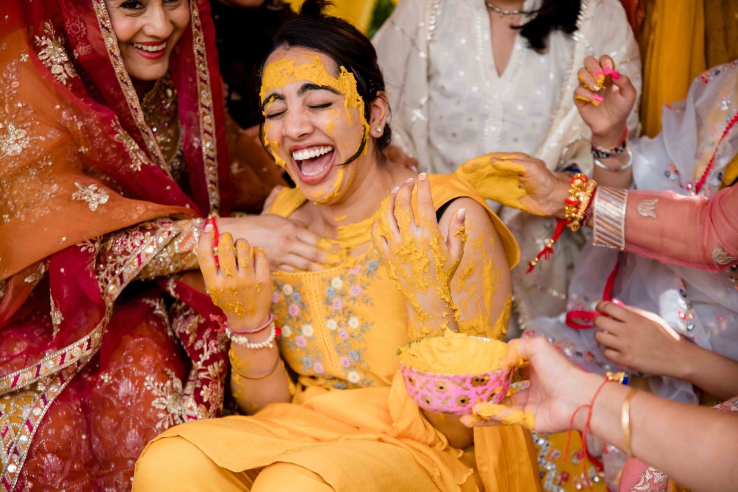 Traditional Haldi ceremony with yellow turmeric powder being applied during wedding ritual.