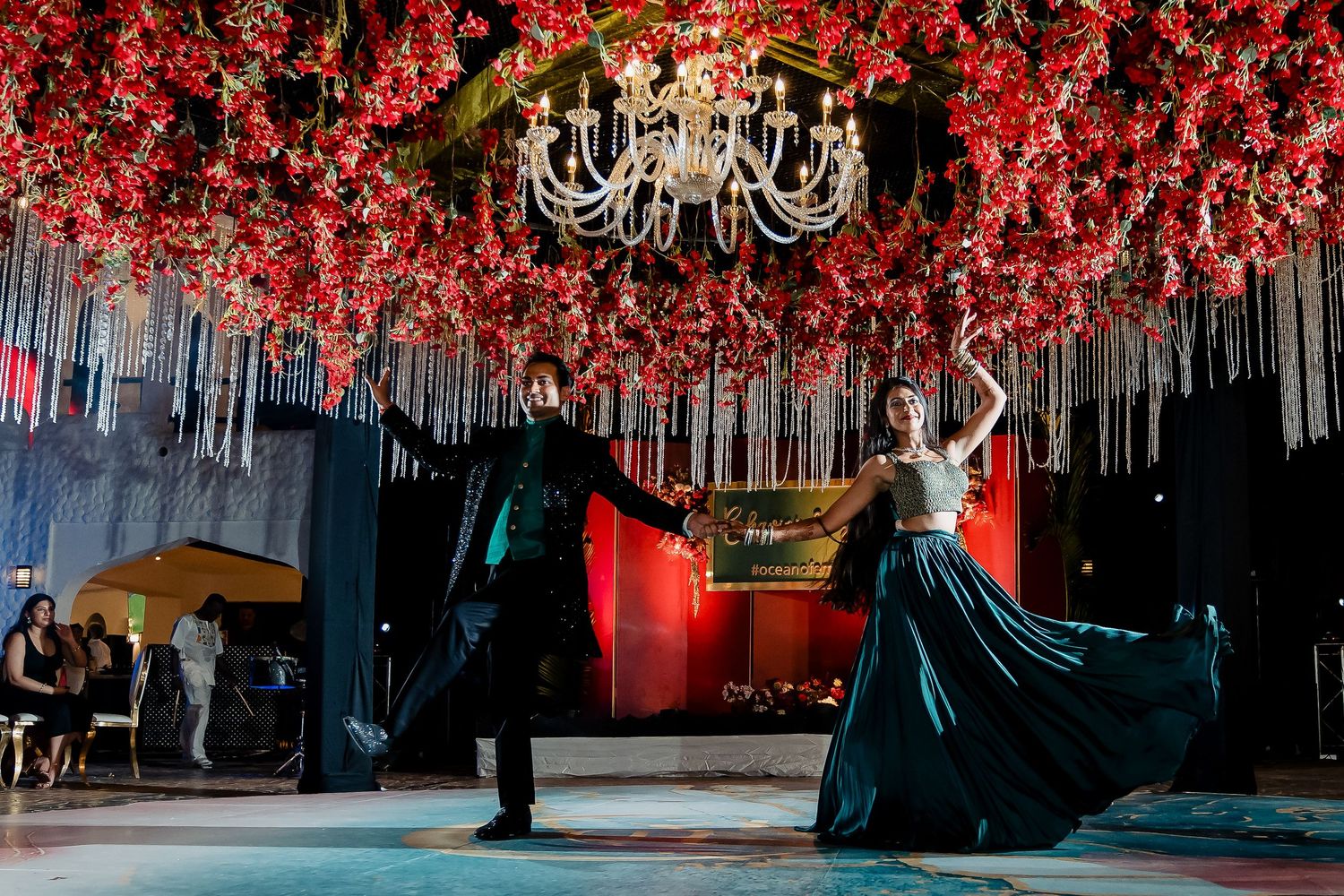 Couple dancing under a spectacular red floral ceiling with crystal chandelier.