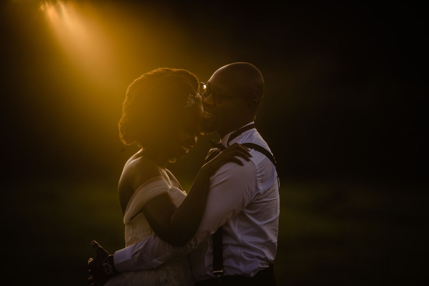 Silhouetted couple embracing under warm dramatic lighting.