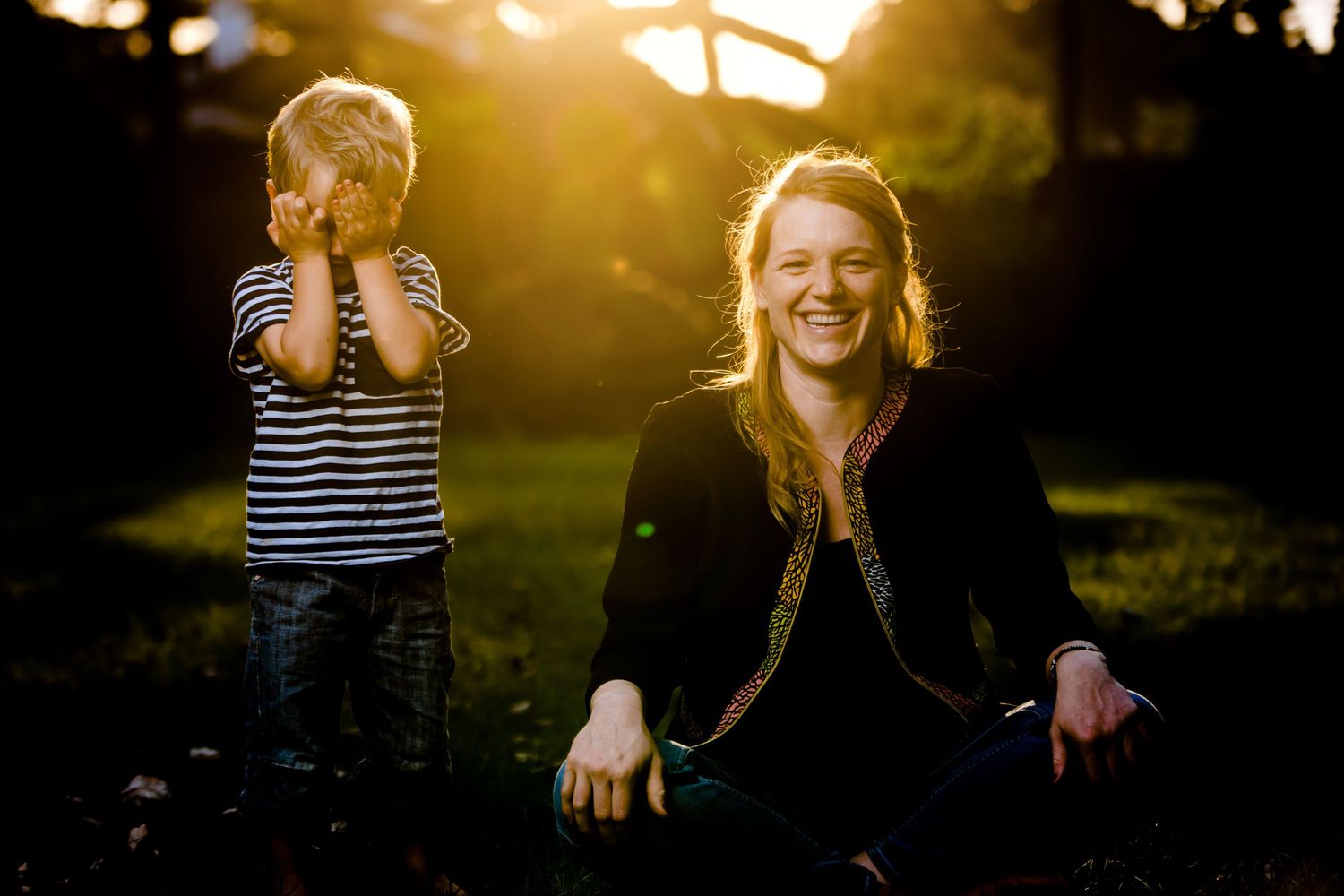 Family playing and laughing together during golden hour sunset outdoors.