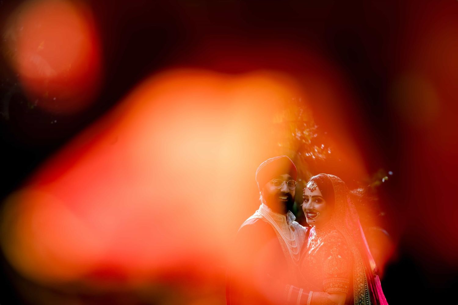Artistic silhouette of wedding couple through bokeh lights creating romantic atmosphere.