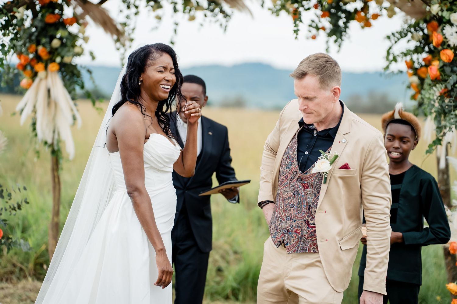 Couple exchanges vows during rustic outdoor wedding ceremony under floral arch.