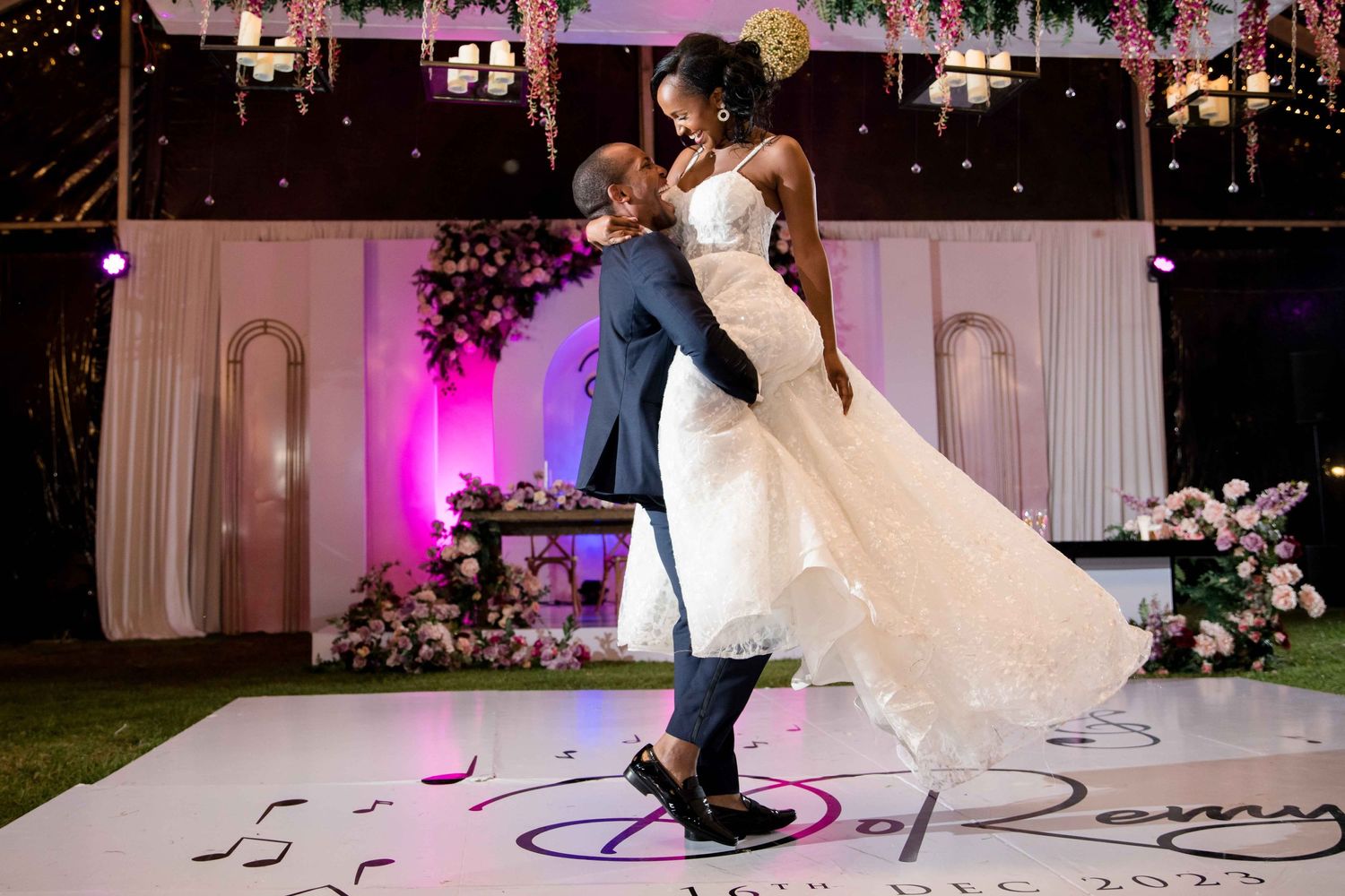 Romantic dance dip on custom monogrammed dance floor with floral decorations.
