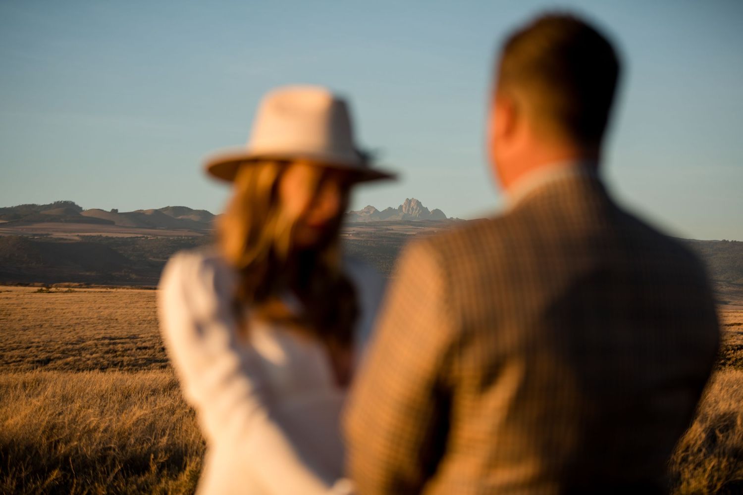 A couple overlooking a desert landscape during golden hour.