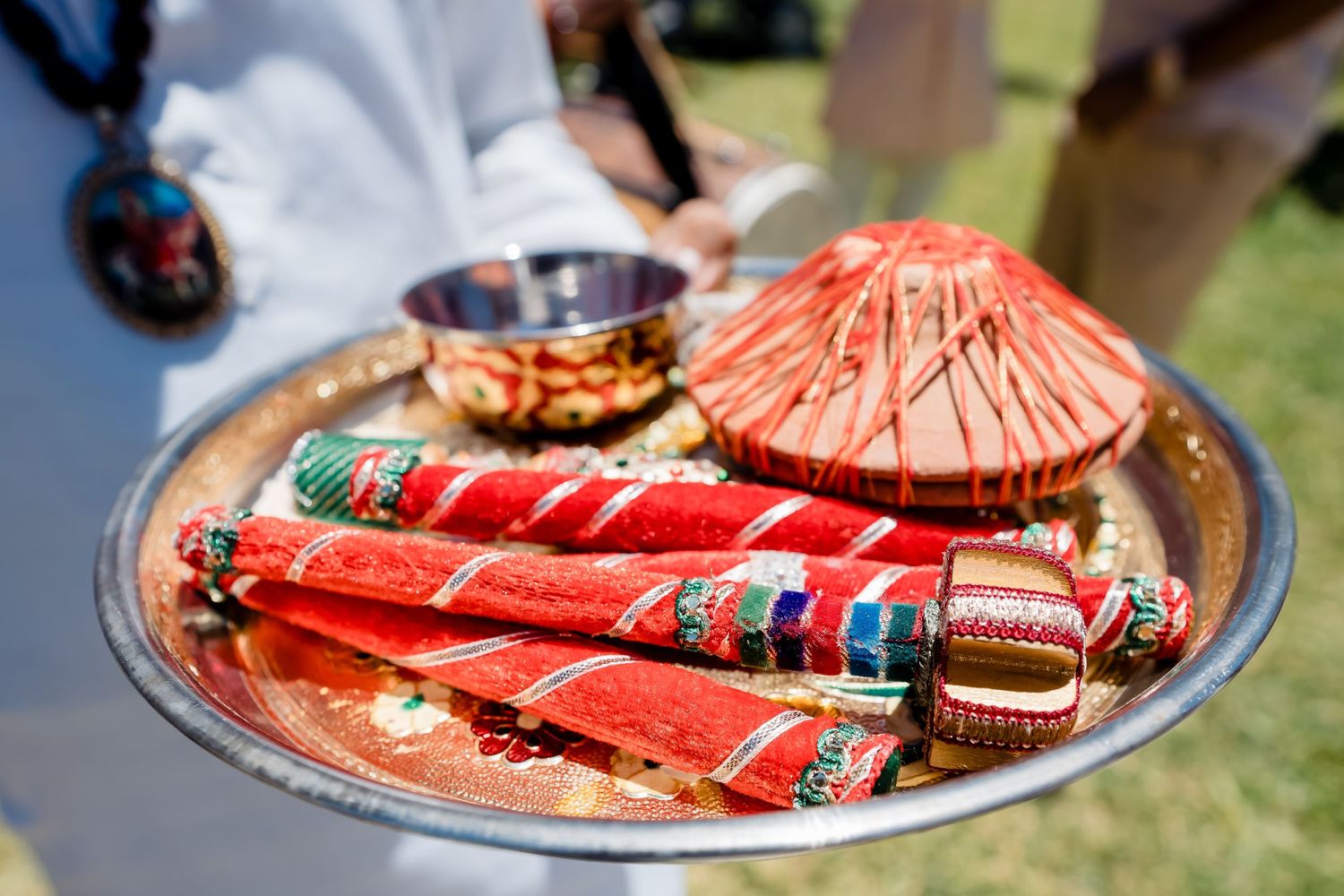 Decorative red party favors and ceremonial items displayed on a silver tray outdoors.