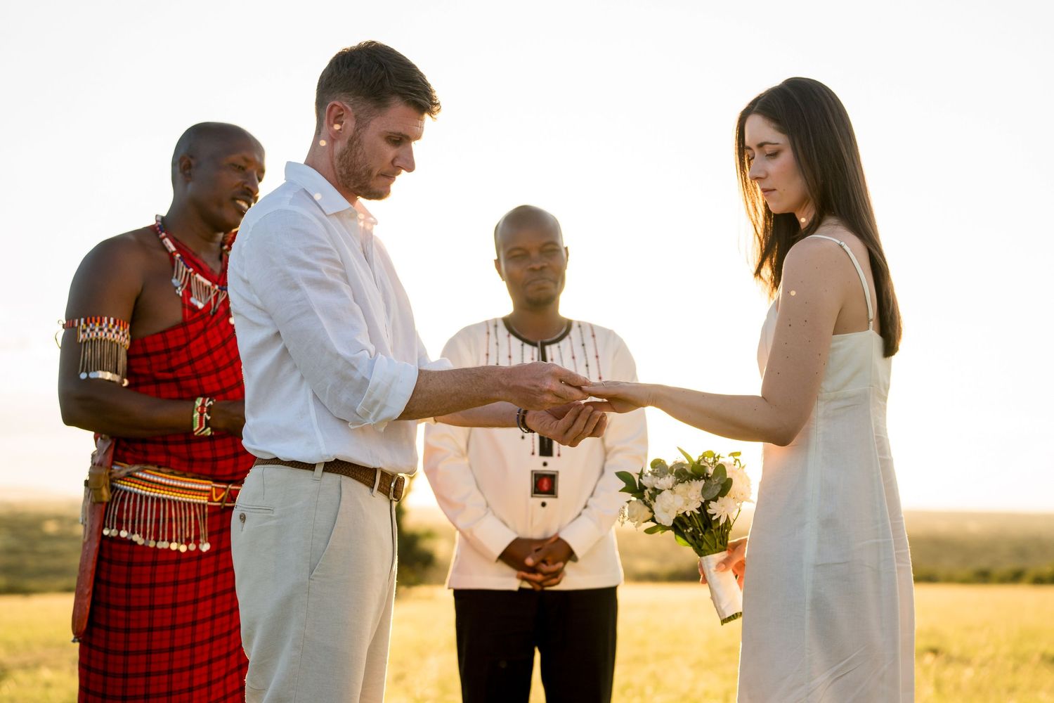 A traditional wedding ceremony takes place outdoors during golden hour in a rural African setting.