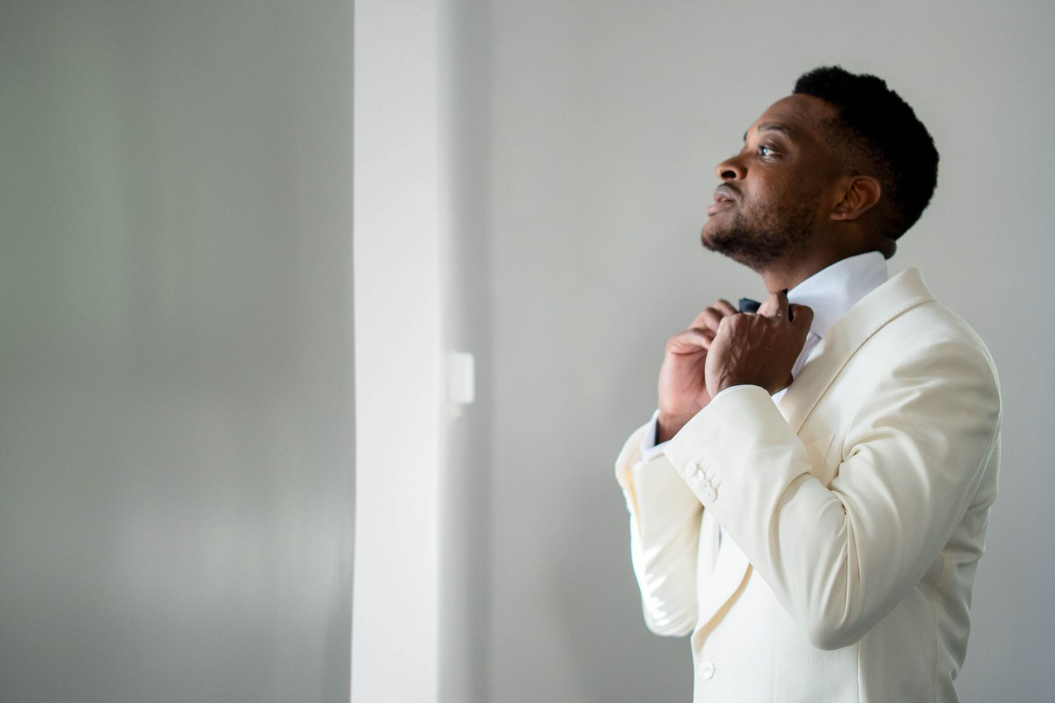A person in a white suit jacket poses against a gray background in a series of expressive shots.