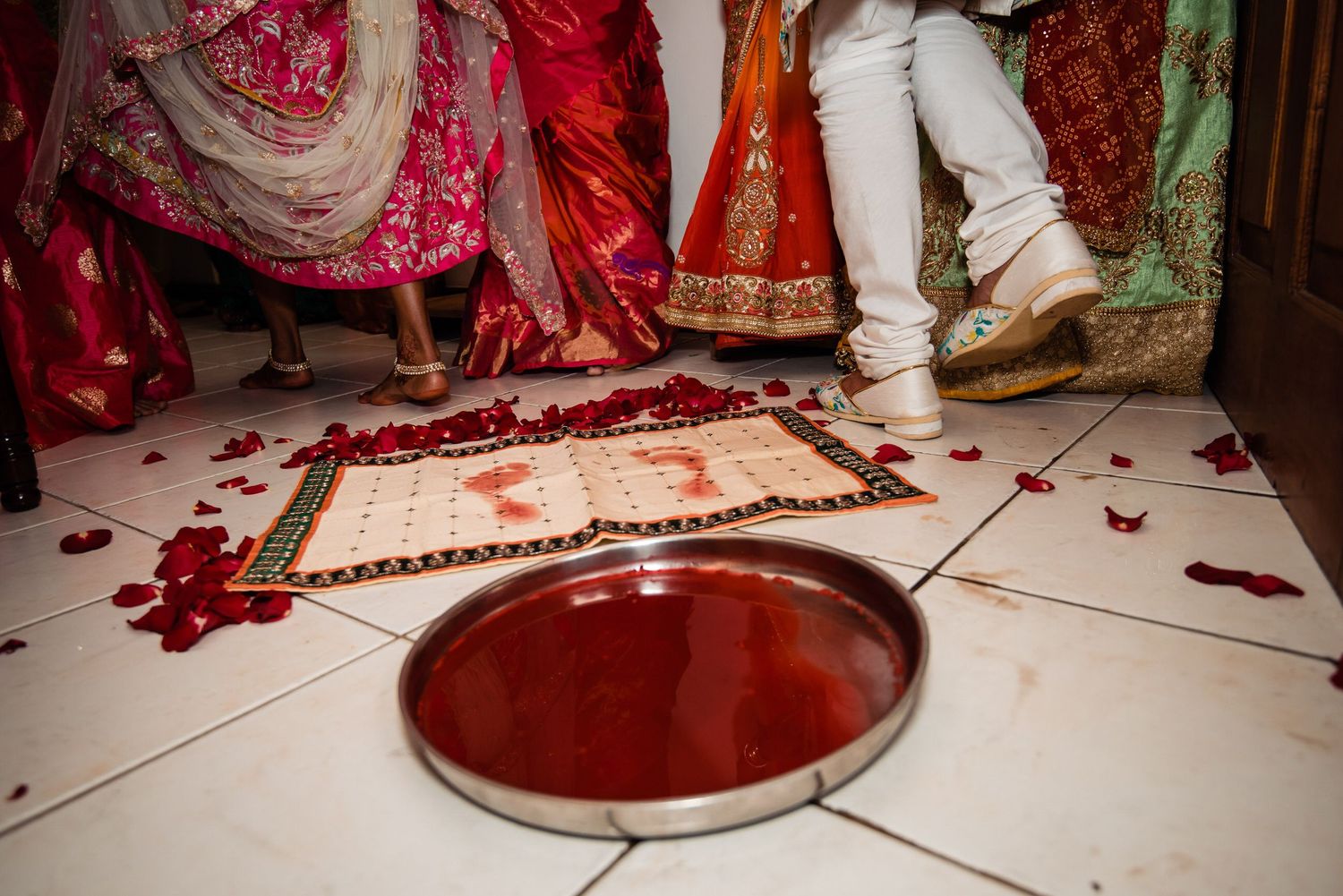 Traditional wedding ceremony setup with red rose petals scattered on white floor.