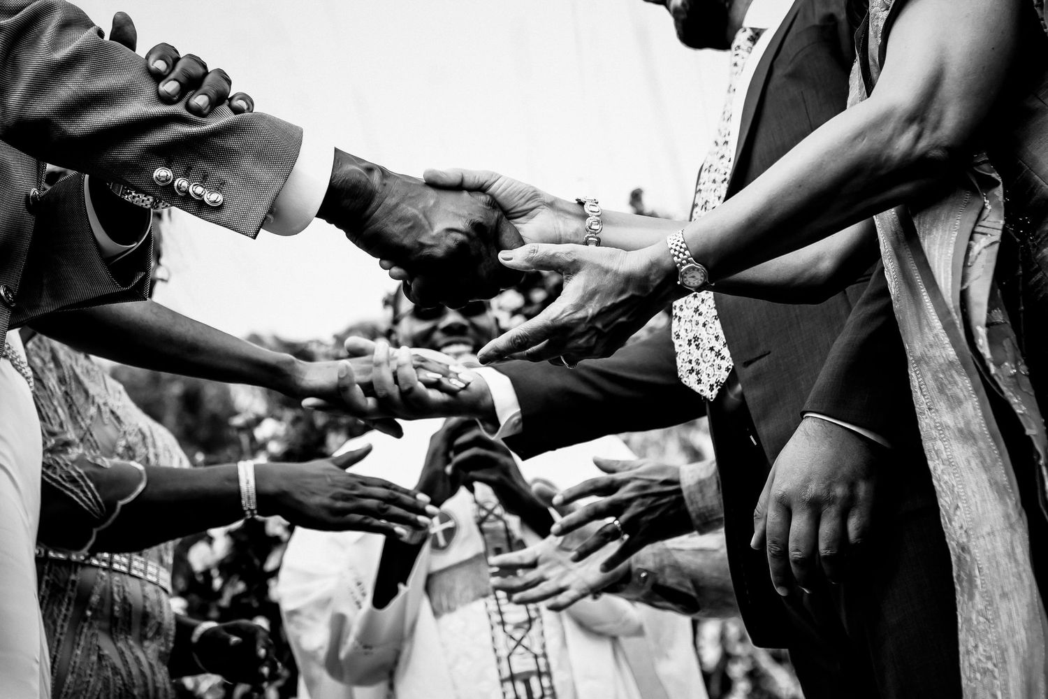 Multiple hands join together in a black and white unity gesture during a celebration.