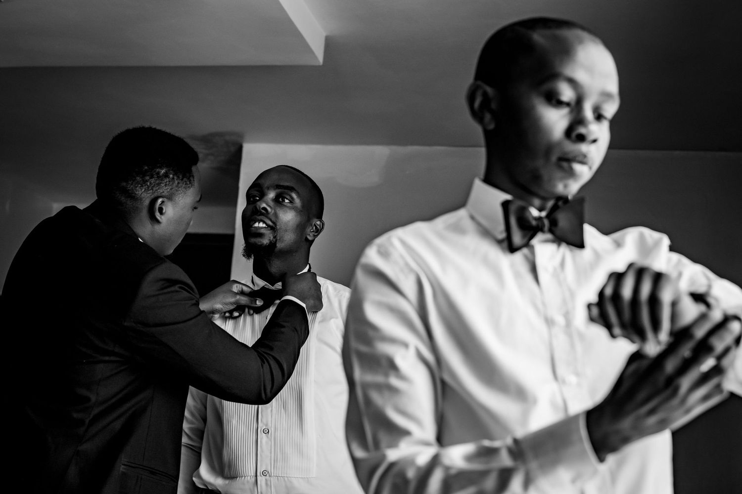 Candid black and white photography captures emotional moments during wedding preparation.