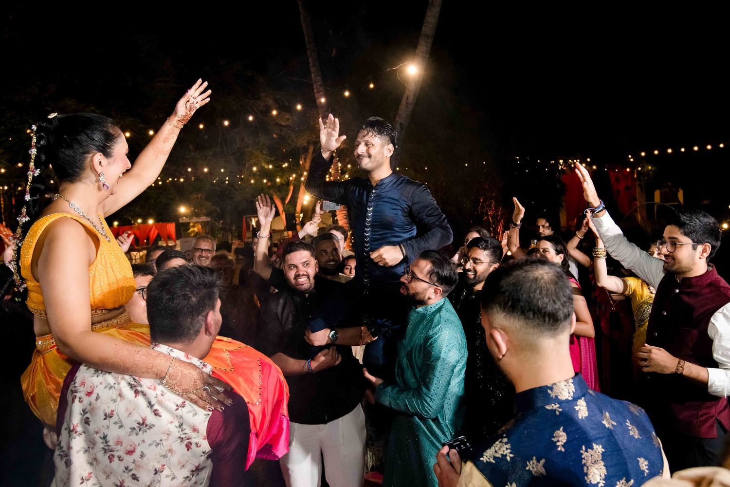 Lively dance floor at a nighttime wedding reception with guests celebrating under festive lighting.