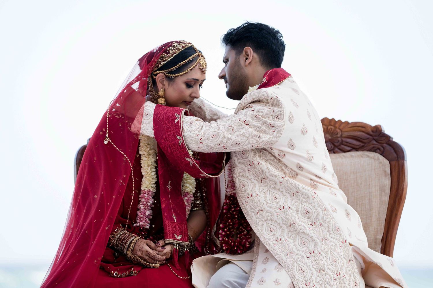 A couple in traditional Indian wedding attire shares an intimate moment during their marriage ceremony.