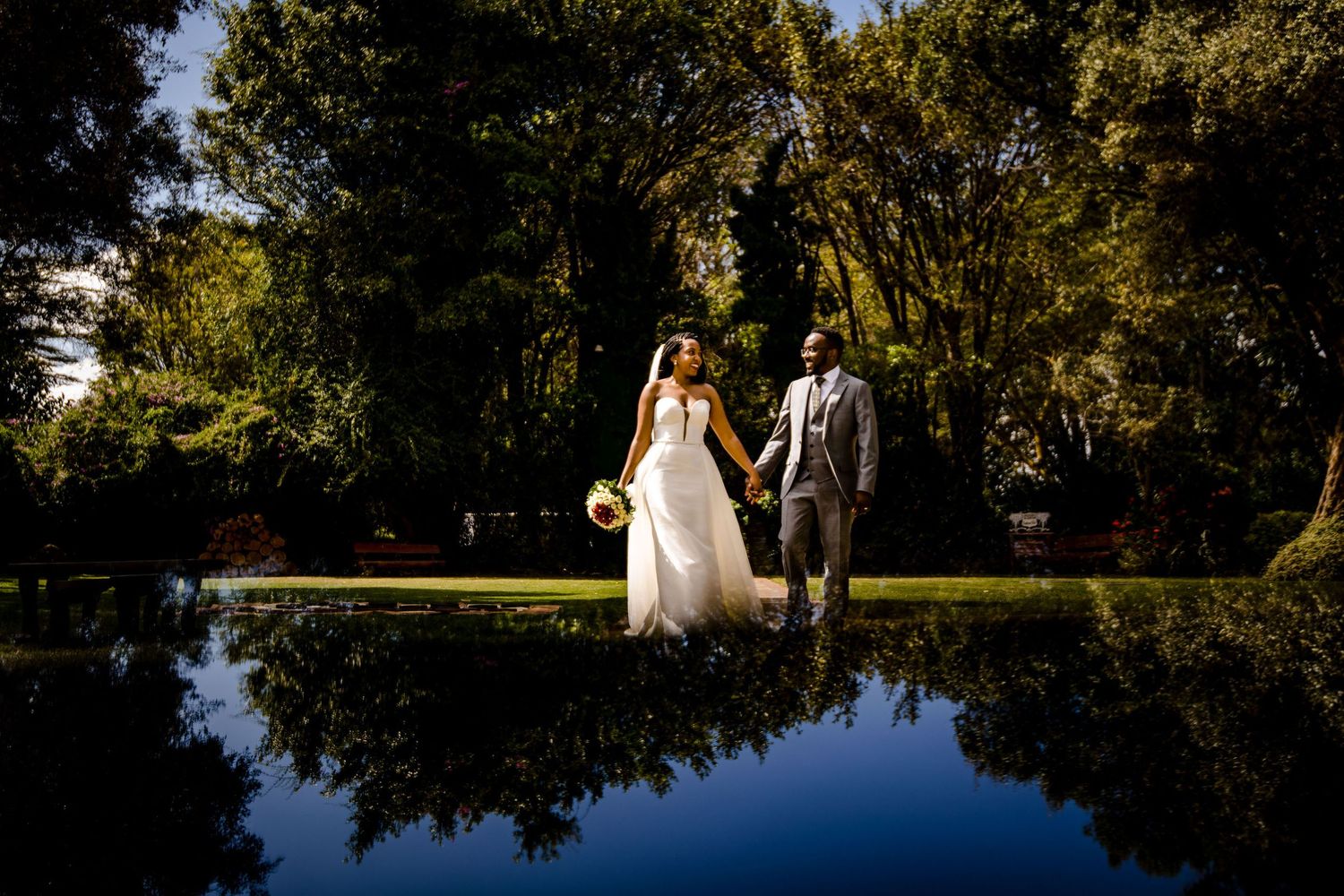 Wedding portraits taken near a serene lake with overhanging trees creating natural framing.