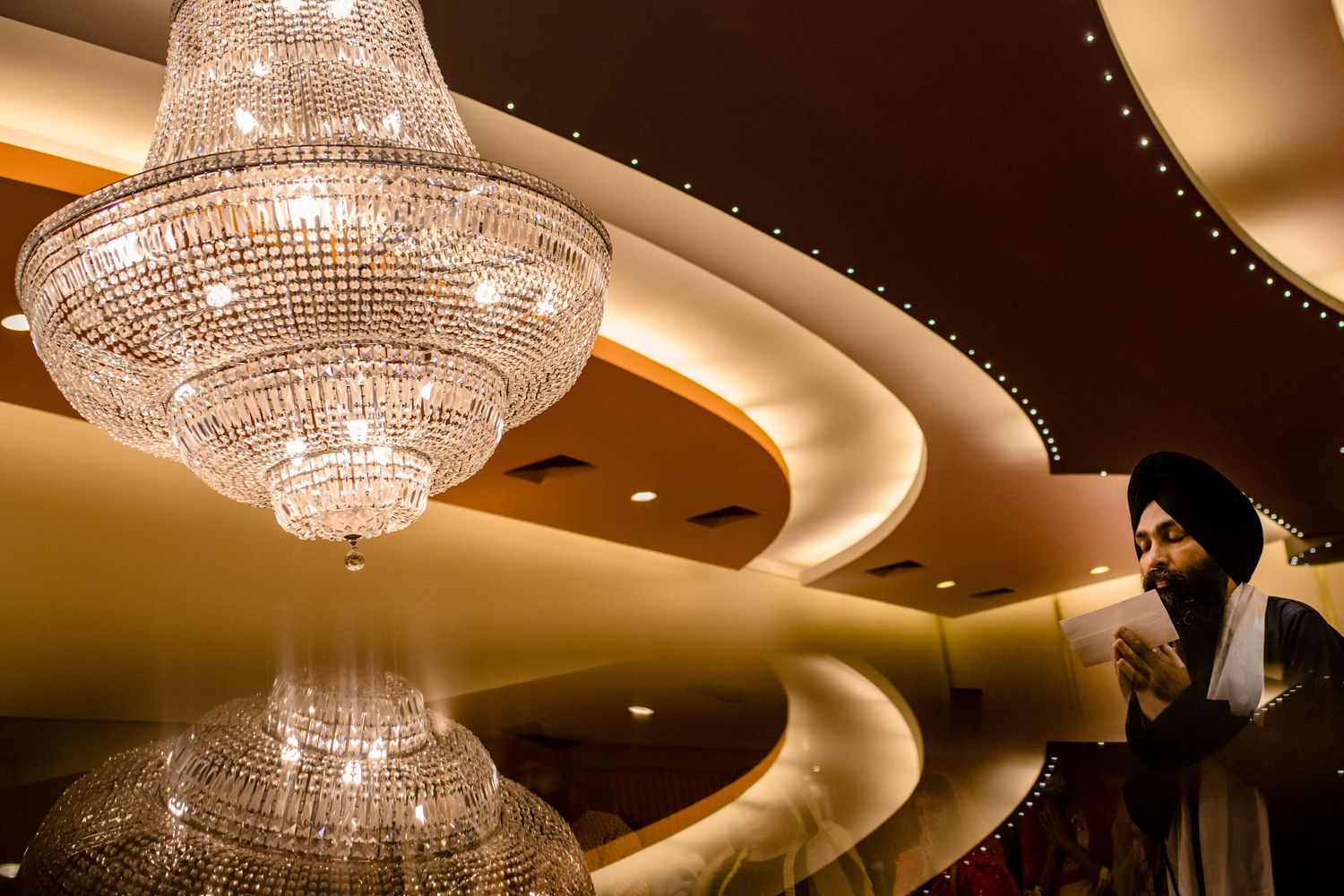 Elegant crystal chandelier hangs beneath curved ceiling with dramatic lighting.