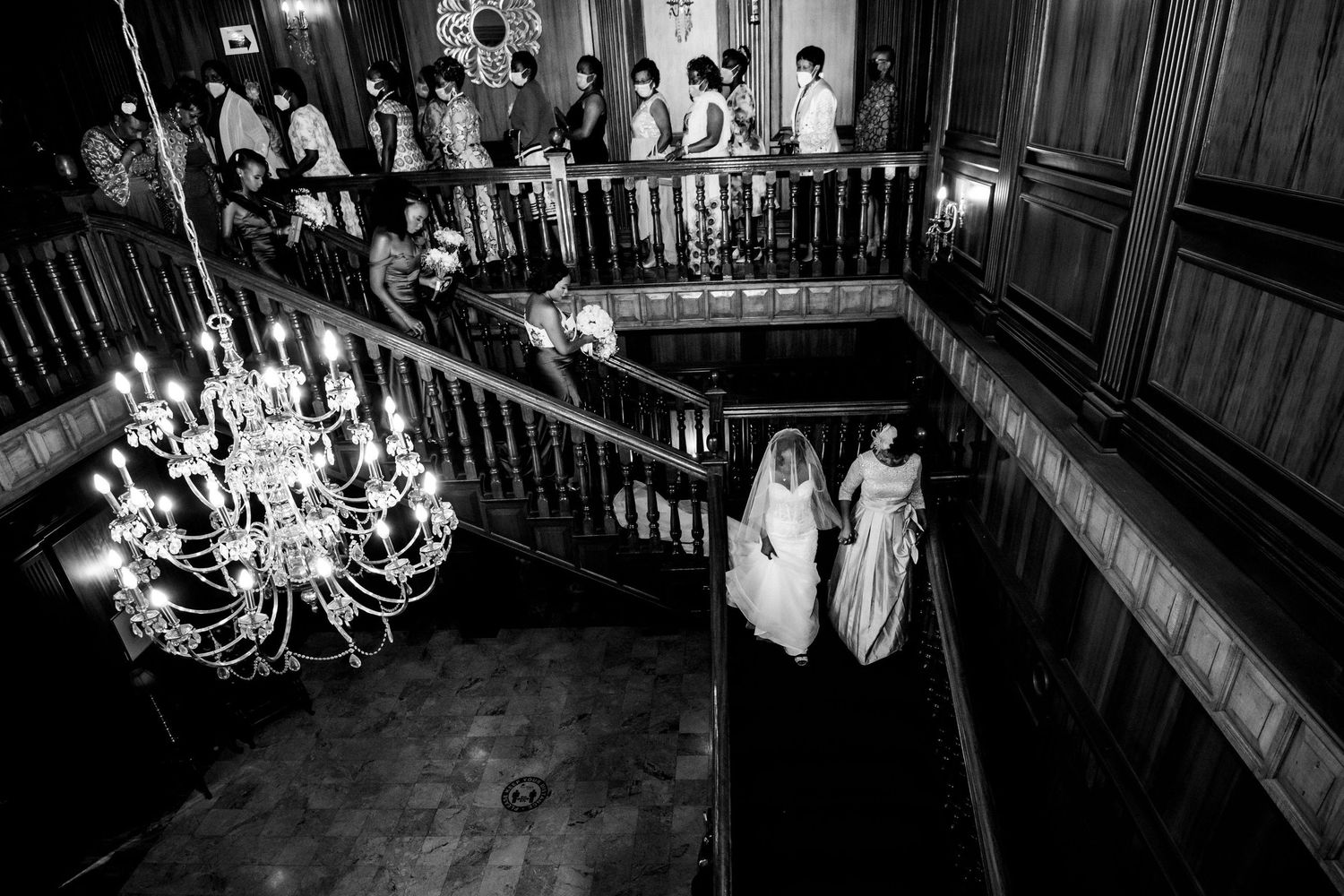 Wide angle black and white photo of wedding guests seated in a historic venue.