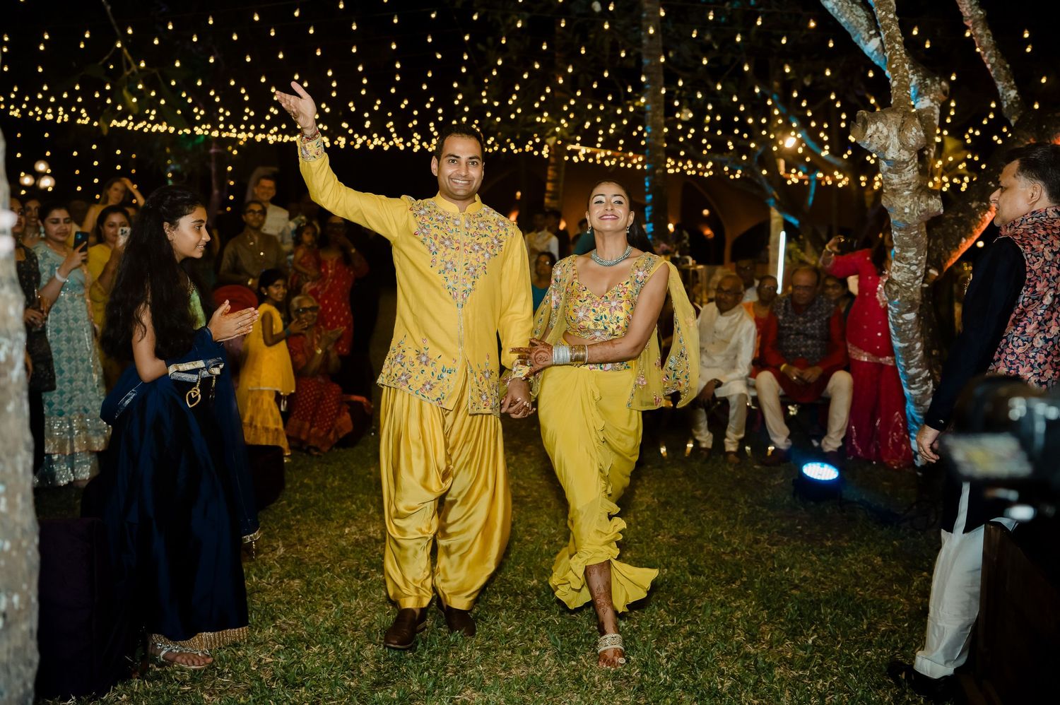 Guests dance under twinkling string lights at an outdoor evening celebration.