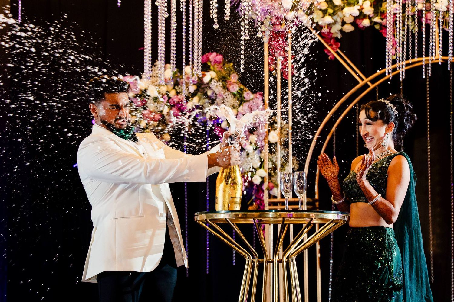 A couple shares a romantic dance moment under sparkling lights and floral decorations at an elegant wedding reception.