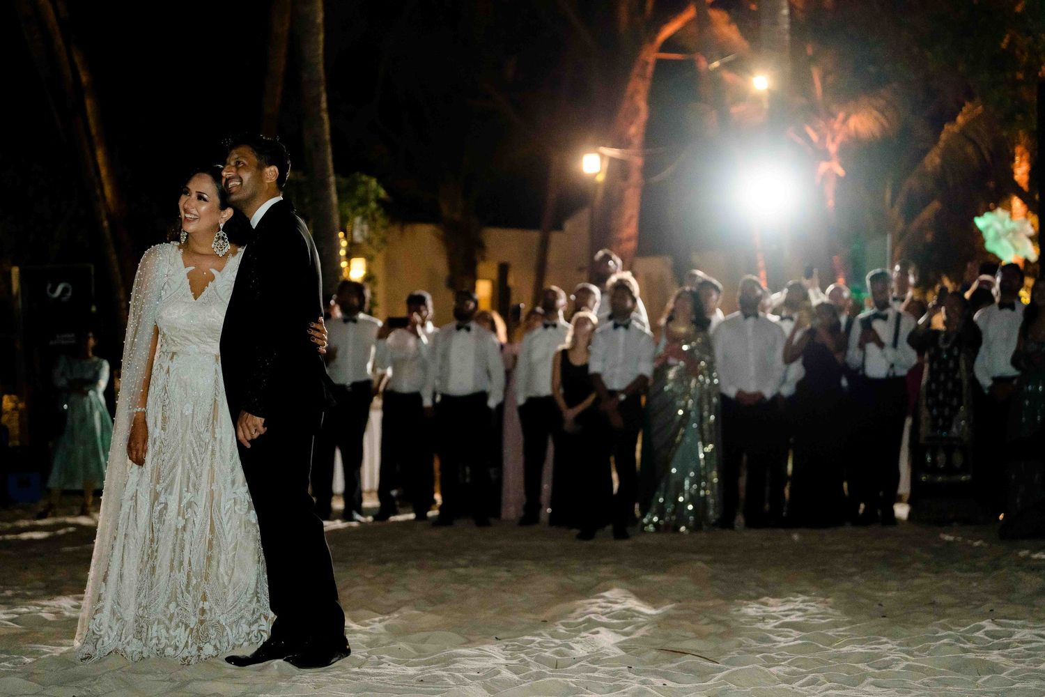 Newlyweds share their first dance together at an evening wedding reception surrounded by guests.