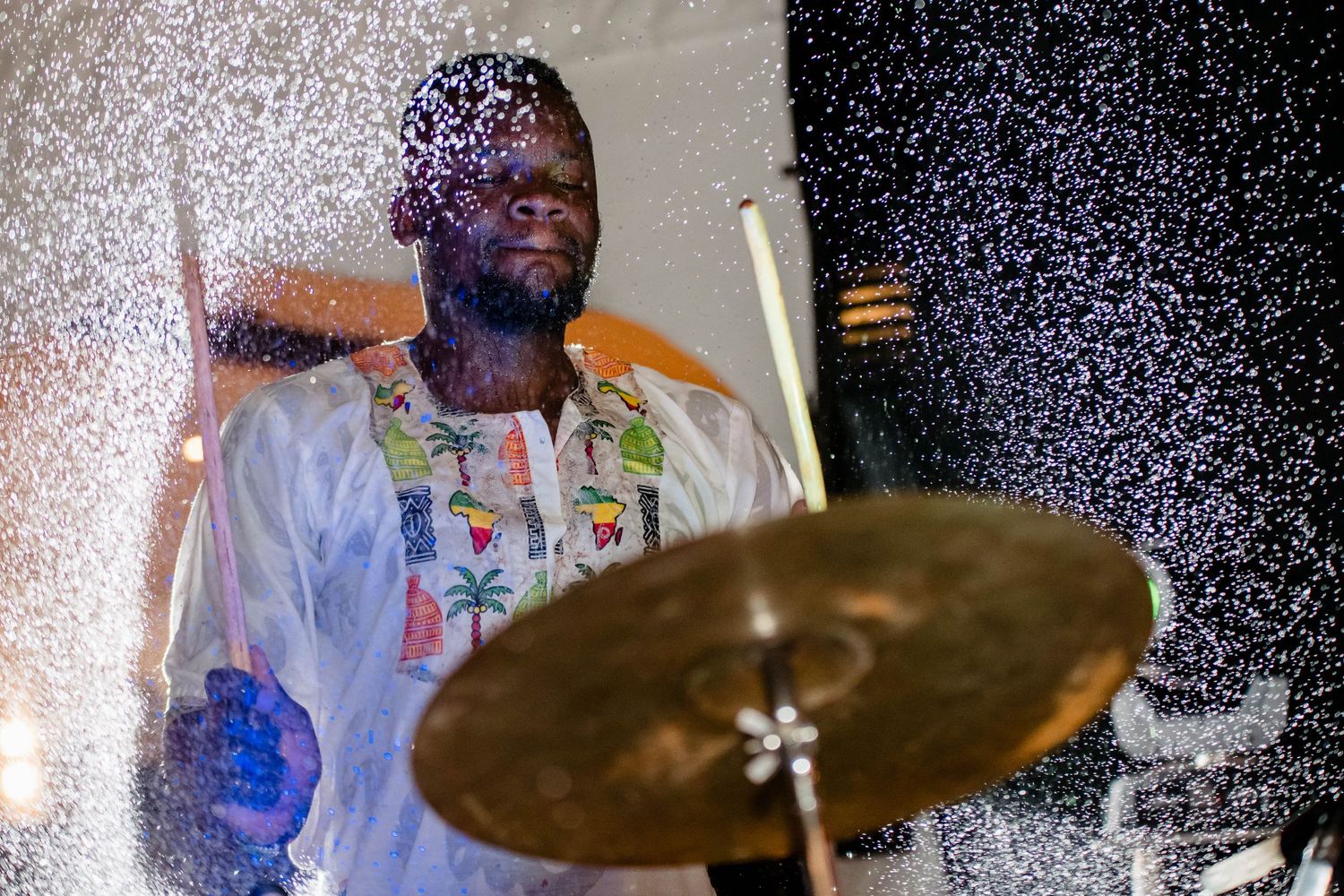Drummer performing on stage amidst dramatic lighting and special effects.