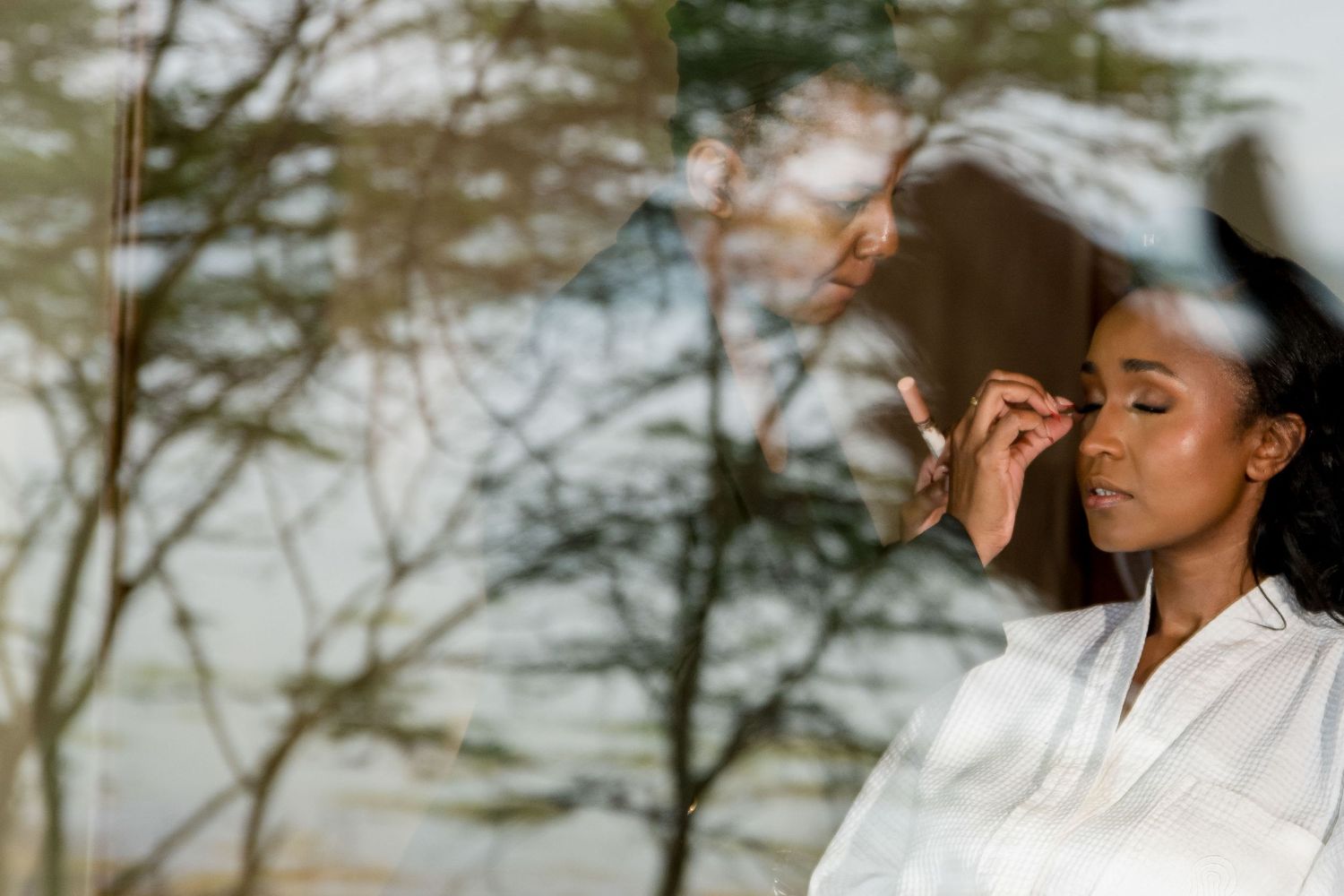 Person in white shirt poses against blurred natural background during outdoor golden hour photoshoot.